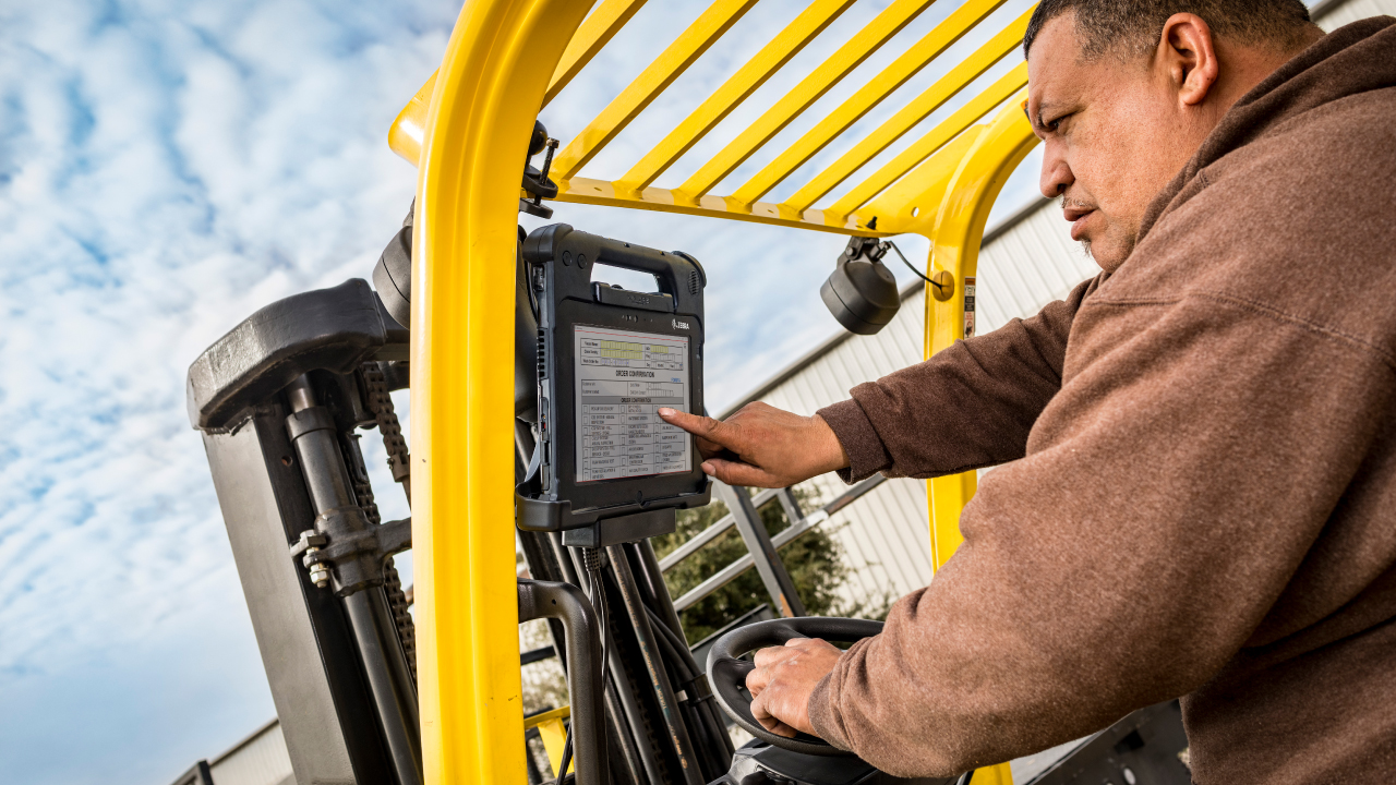 A forkfift operator looks at the scren of the rugged tablet mounted in his vehicle