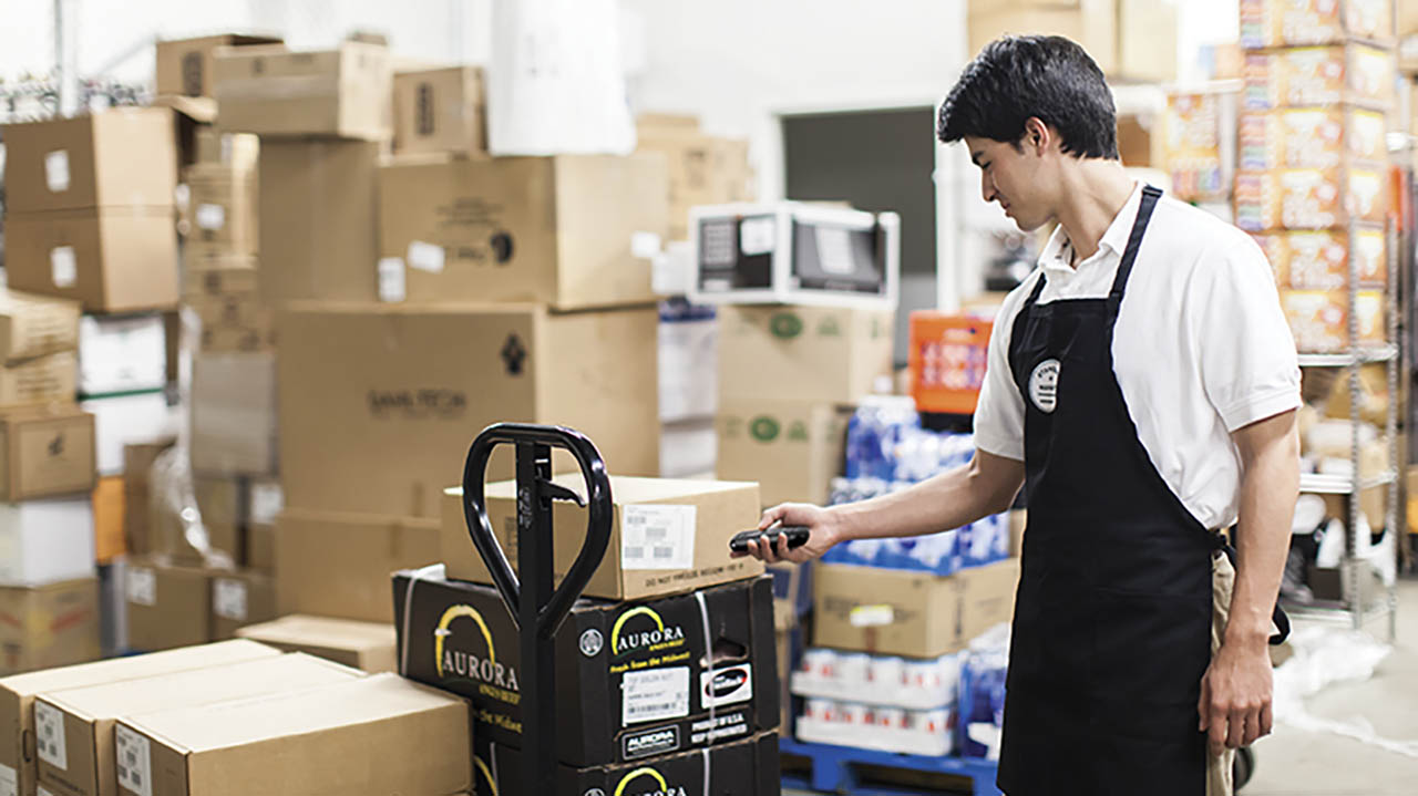 A grocery store associate uses a Zebra CS60 to scan a box of produce in the back of the store.