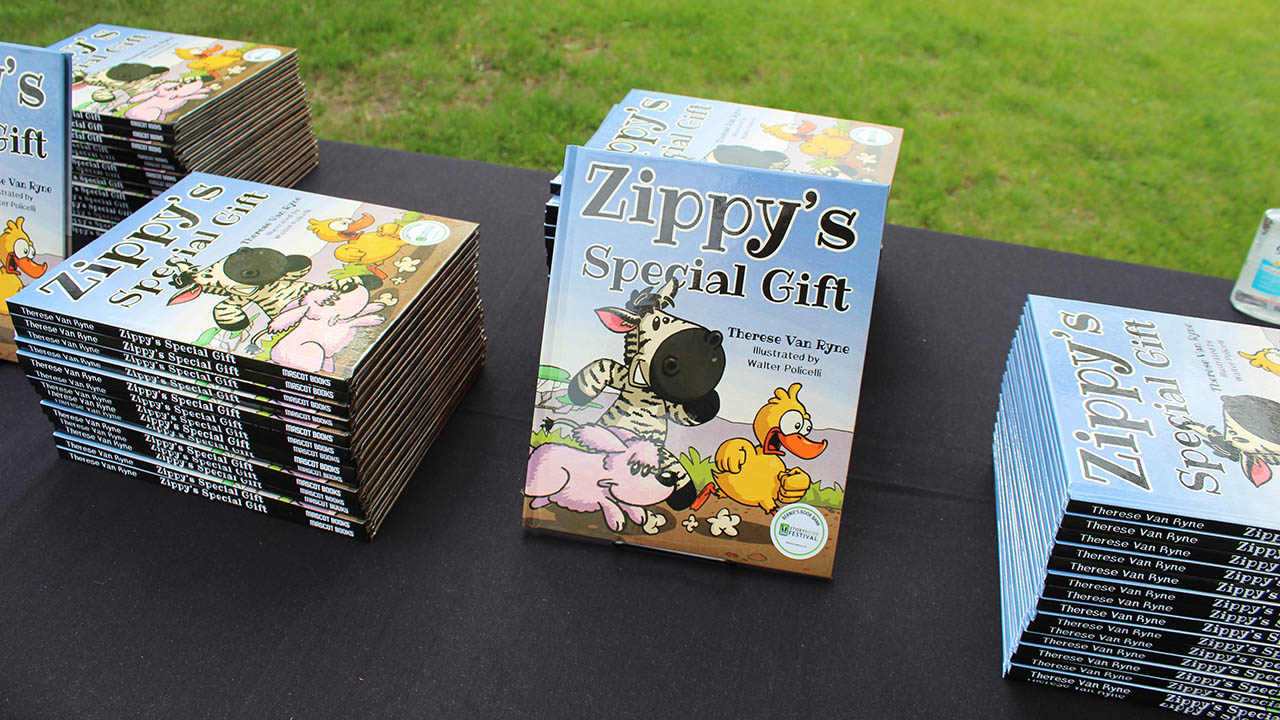 Several copies of the children's book Zippy's Special Gift sit on a table.