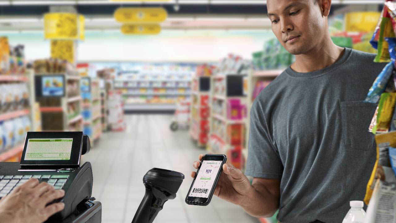 A convenience store customer uses a contactless scanner to redeem loyalty rewards