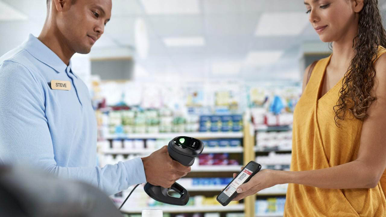 A drug store associate uses a Zebra DS9900 Series barcode scanner to scan a customer's digital loyalty card barcode