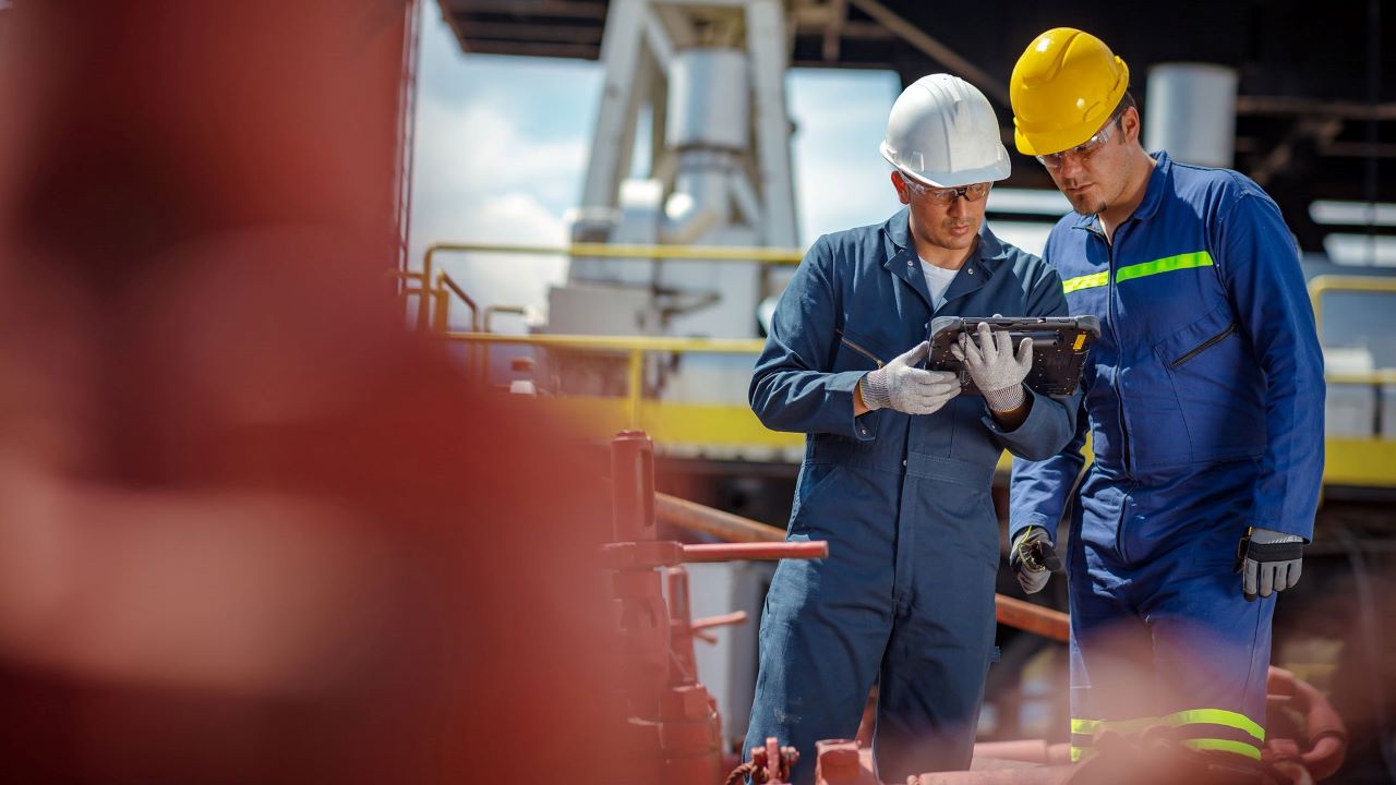 Two energy company workers look at a rugged tablet screen