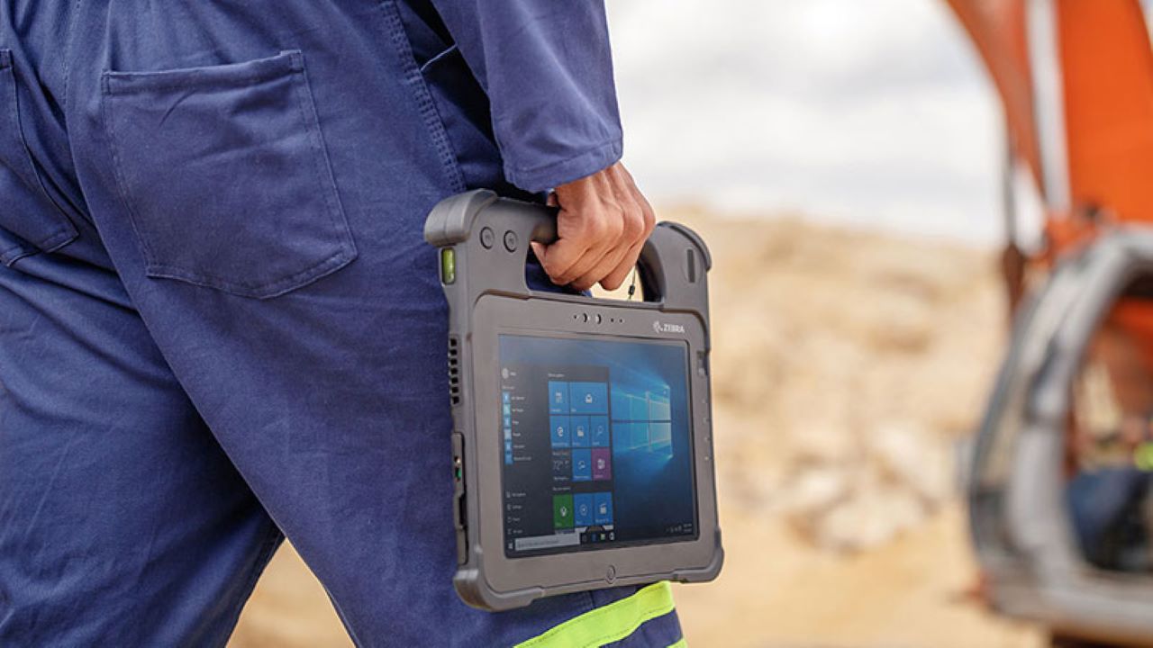 A field service technician carries a Zebra L10 XSLATE rugged tablet