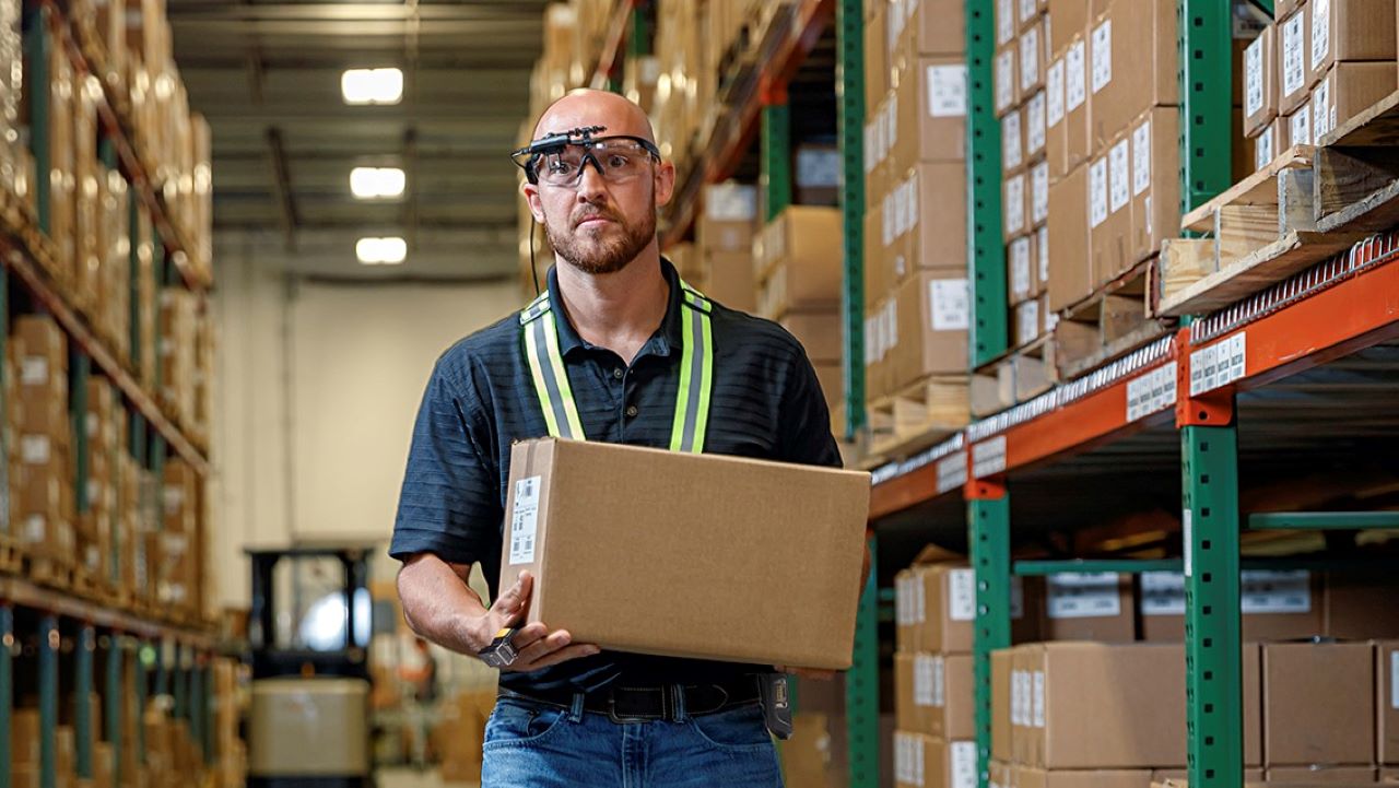 A warehouse workers uses the new Zebra HD4000 head-mounted display to retrieve a box.