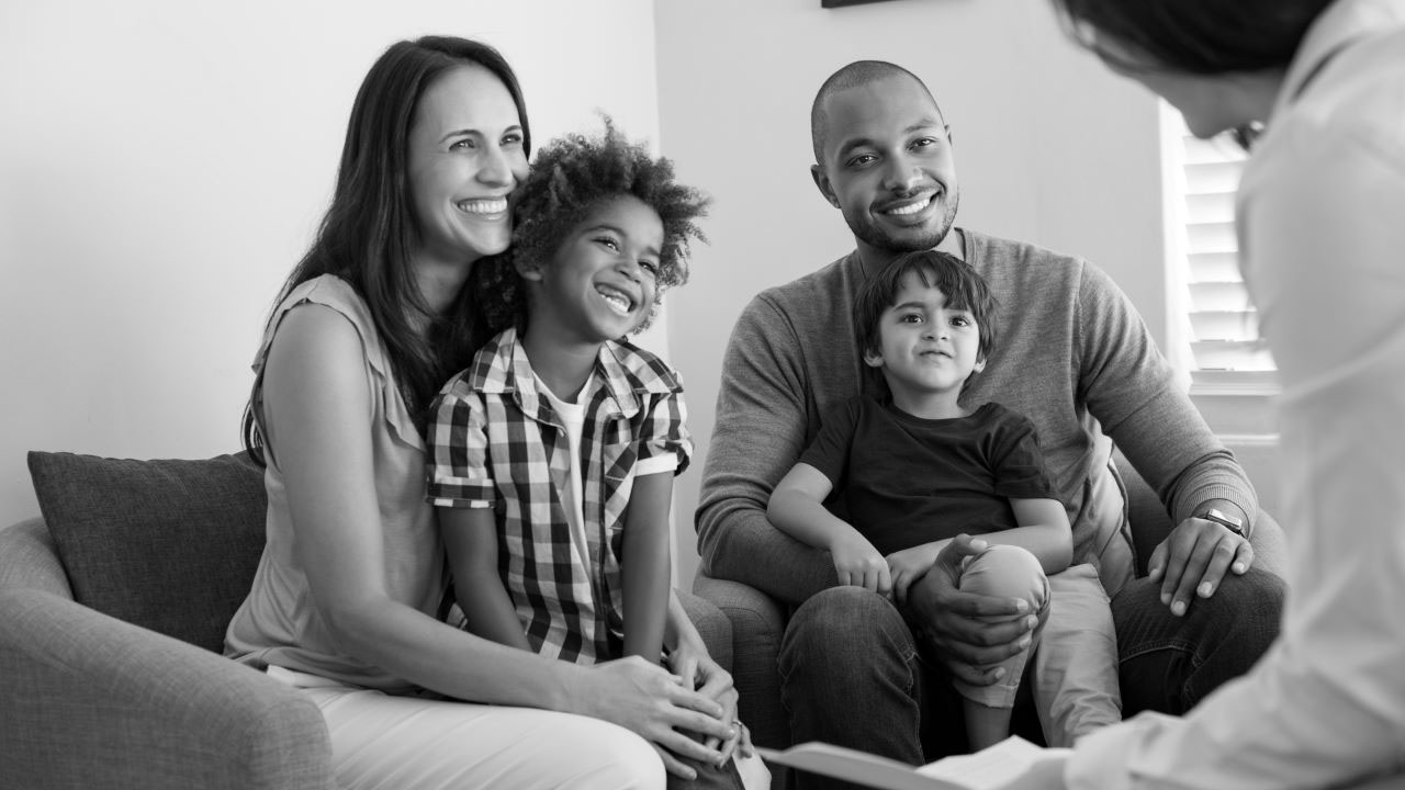 A family sits on a couch and talks to a benefits counselor.