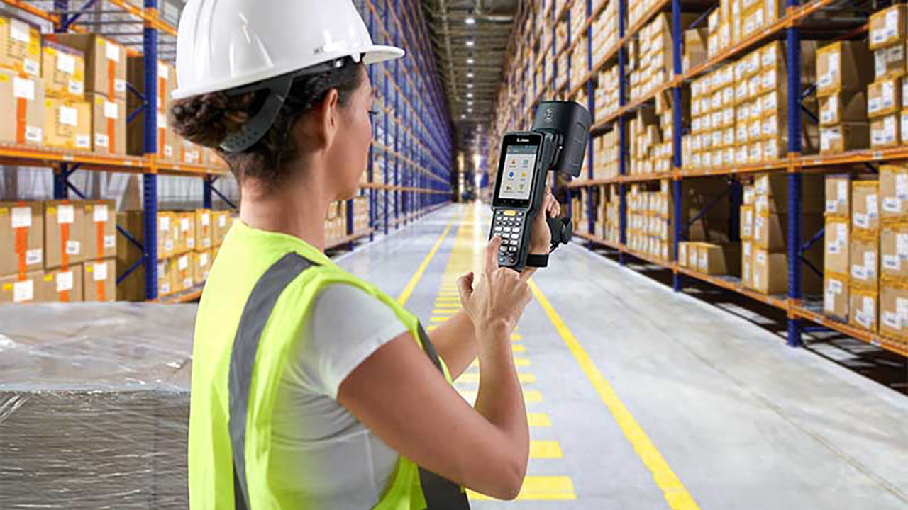 A warehouse worker looks at a handheld RFID reader