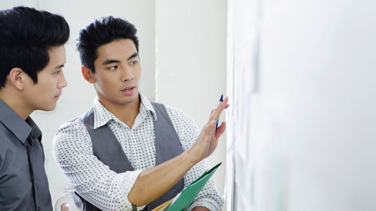 Two men look at a whiteboard