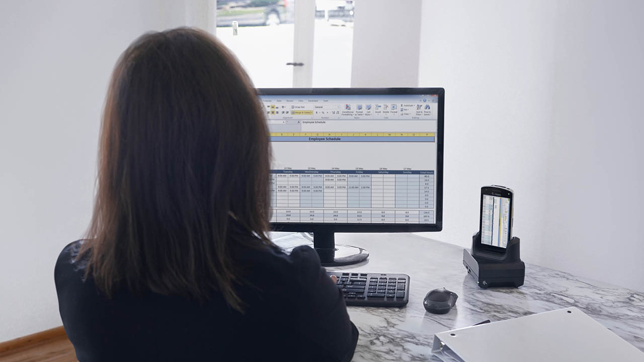 A woman looks at a spreadsheet on her desktop computer monitor