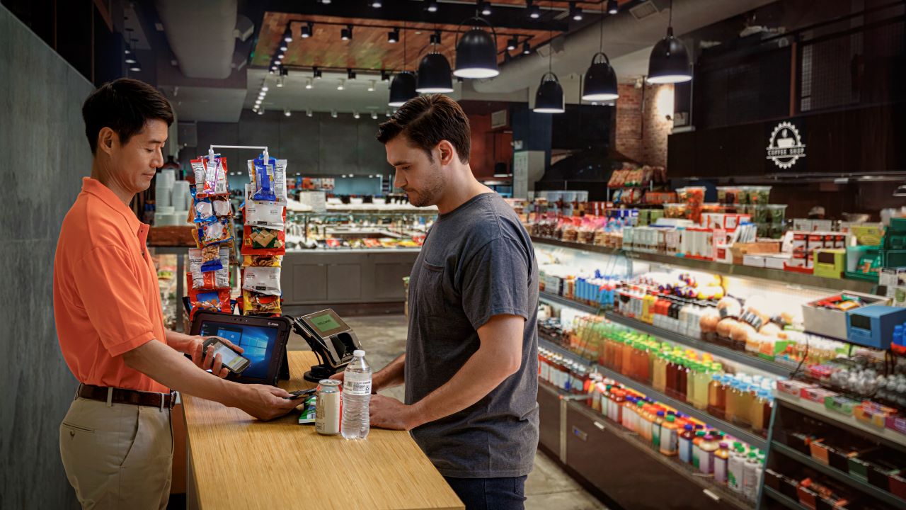 A convenience store employee rings up a customer's order at the register