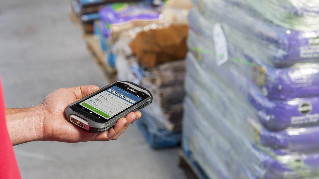 A home improvement store associate uses a Zebra TC52ax mobile computer to scan mulch bags