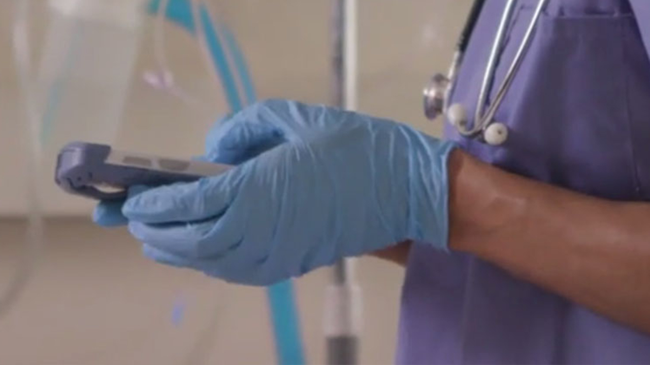 A nurse looks at a shared clinical smartphone.