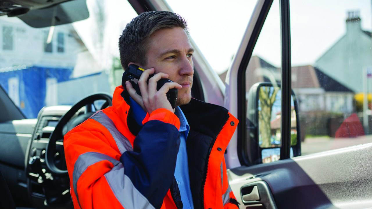 A postal service workers talks on a Zebra TC77 handheld mobile computer