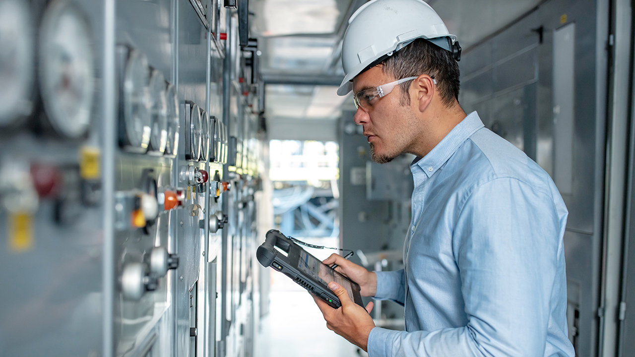 A utility worker uses a Zebra L10 XSLATE rugged tablet to input data he's reading from a meter