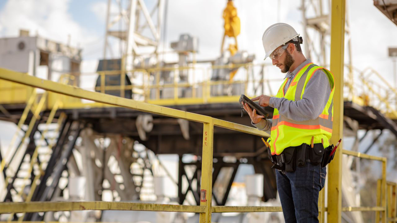  A utility field technician looks at his tablet while standing on a catwalk
