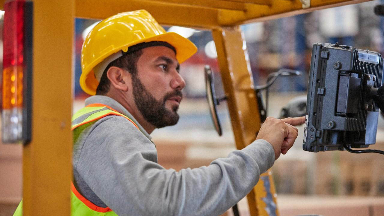 A forklift operator touches the screen of a Zebra VC8300