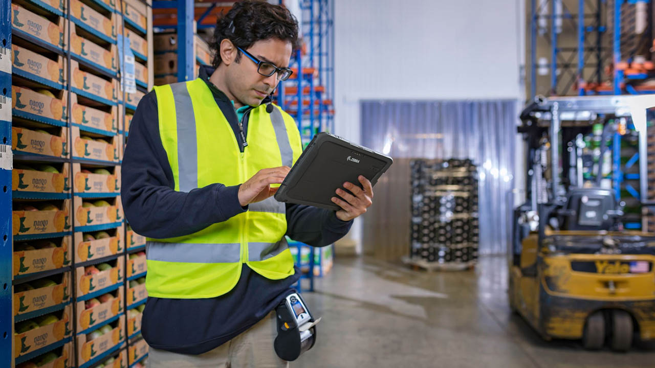 A produce warehouse worker looks at a rugged tablet 