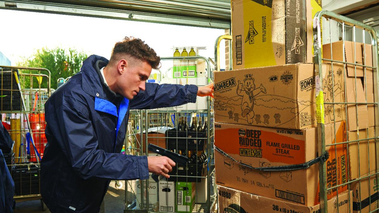 A warehouse worker uses a purpose-built rugged mobile computer to scan inventory on the loading dock.