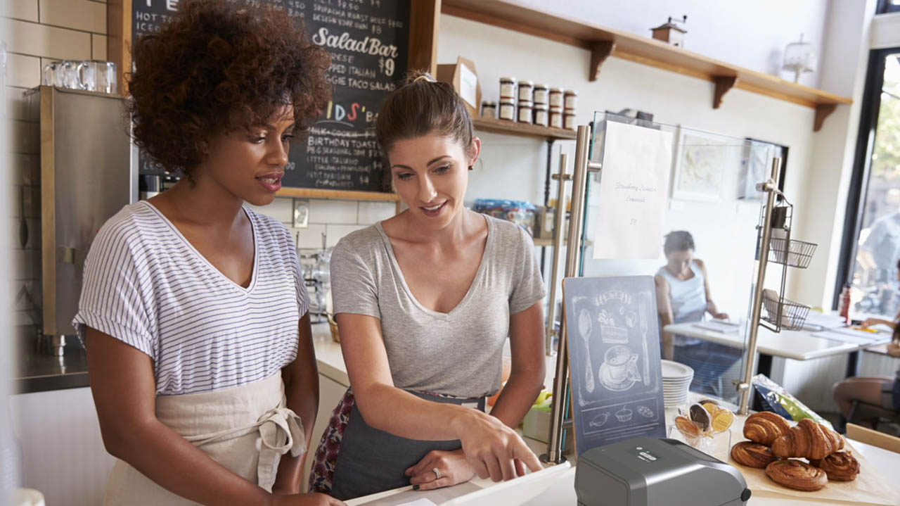 Two bakery shop workers talk near the counter