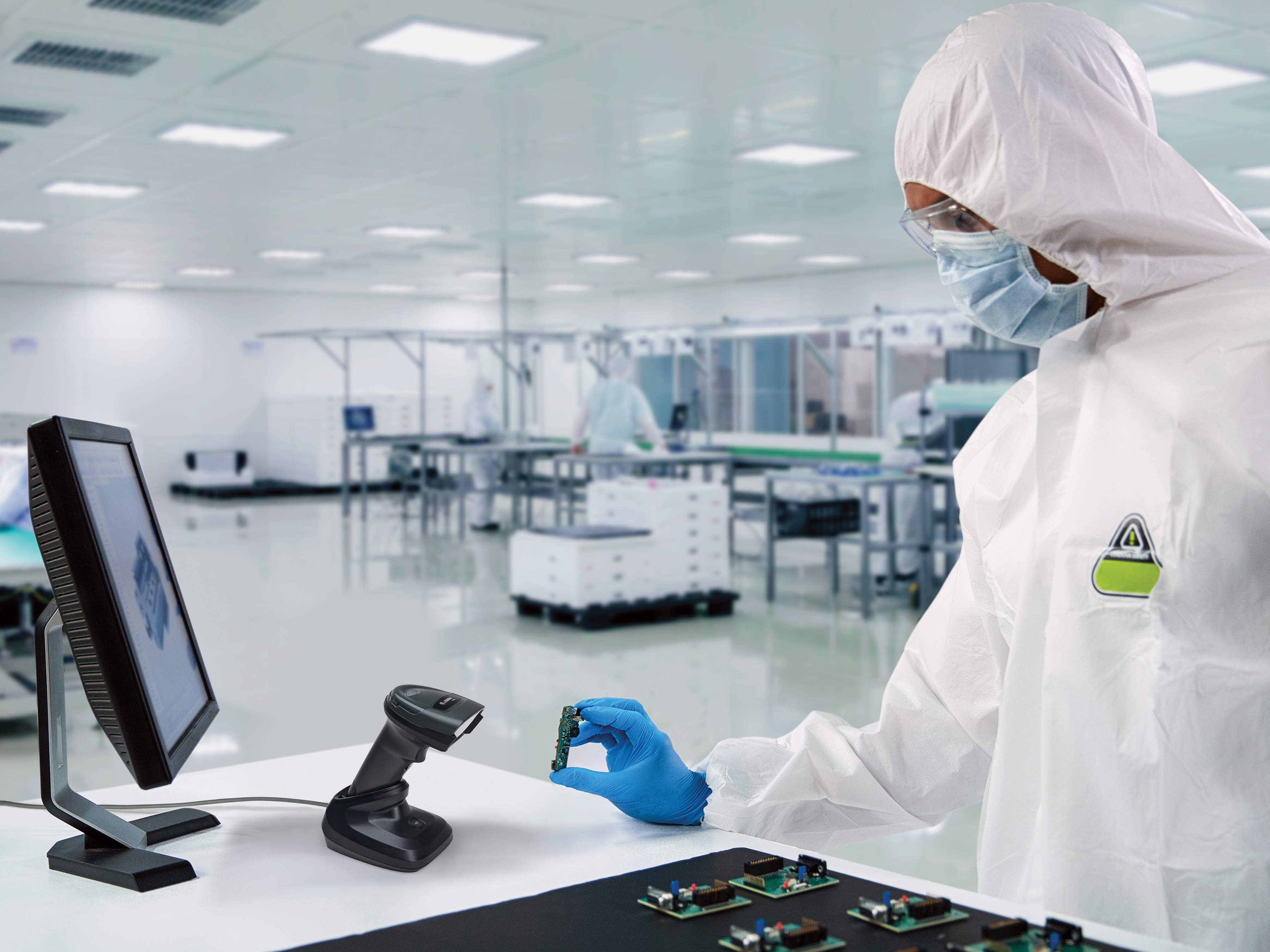 Worker using a Zebra hands-free scanner in a cleanroom environment.