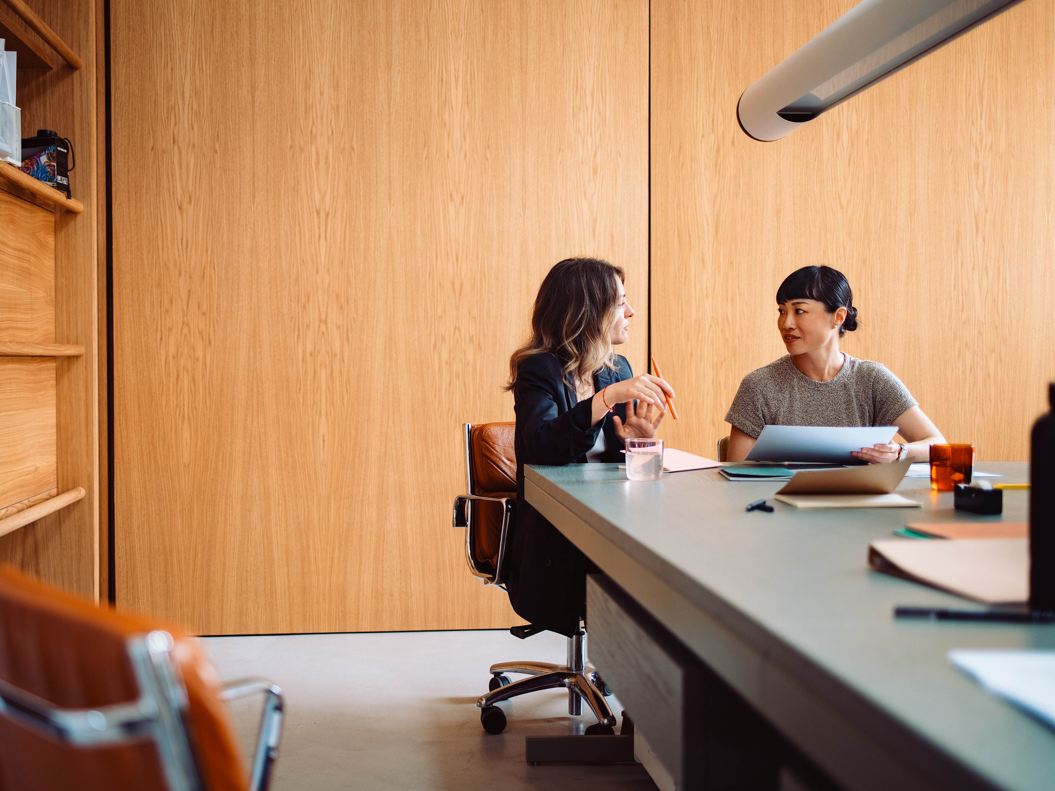 Two professionals collaborating in an office boardroom.