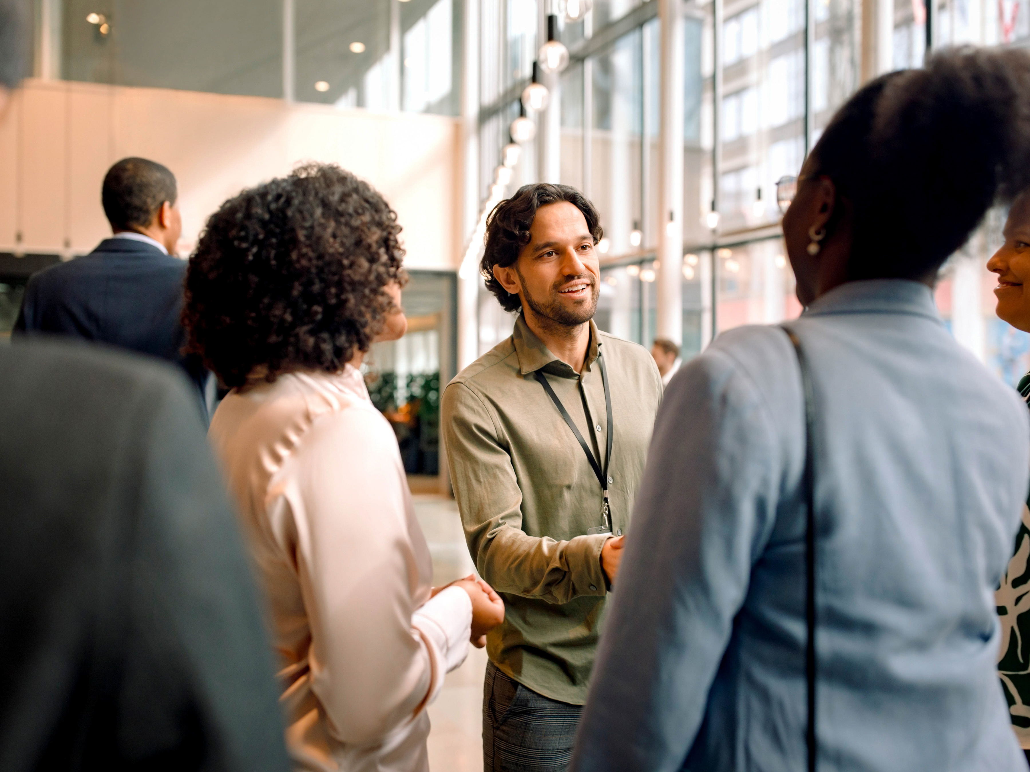 A group of professionals are meeting one another and exchanging handshakes at a conference center.