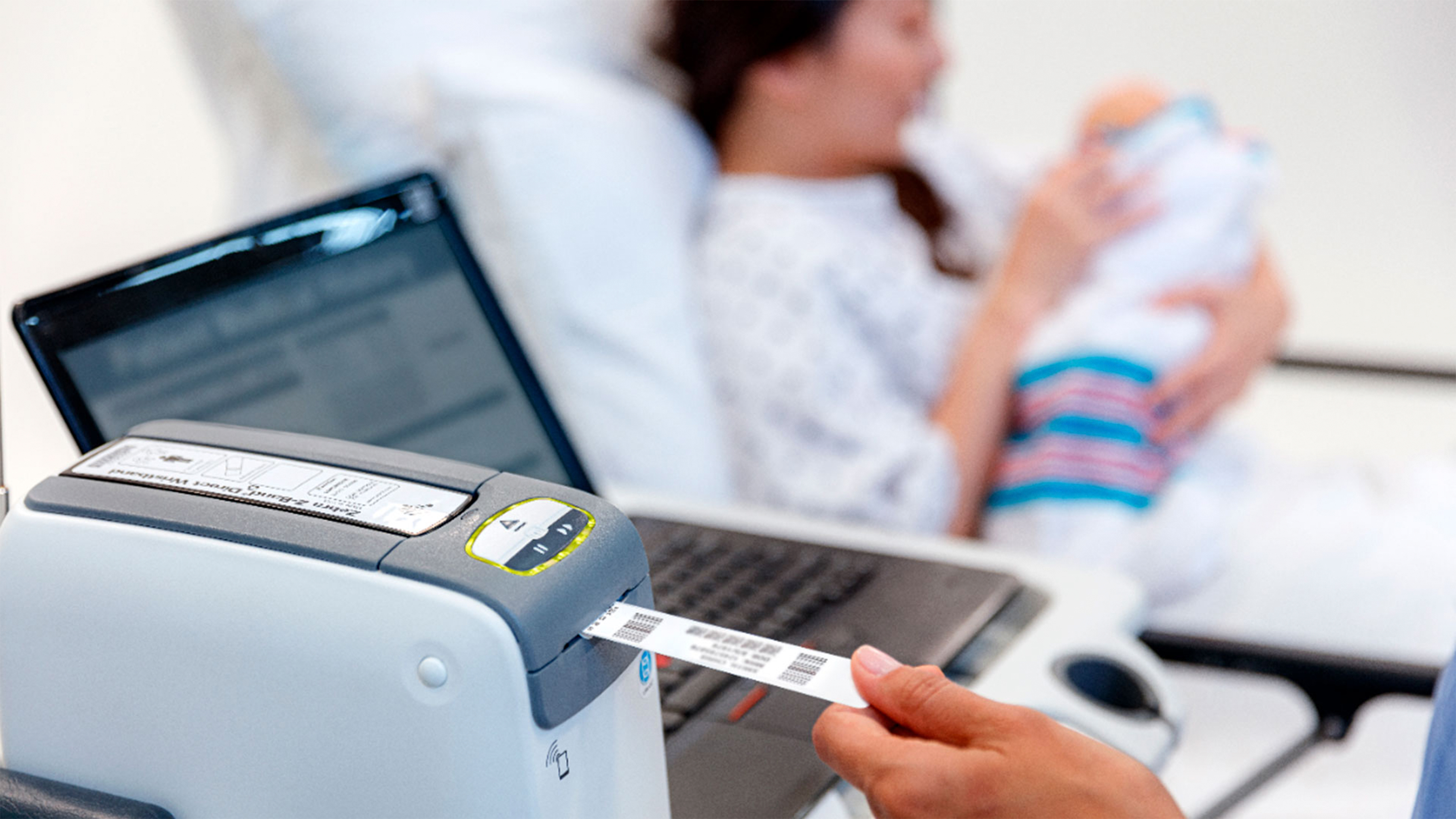 Health professional using a Zebra desktop printer to label a patient wristband. 
