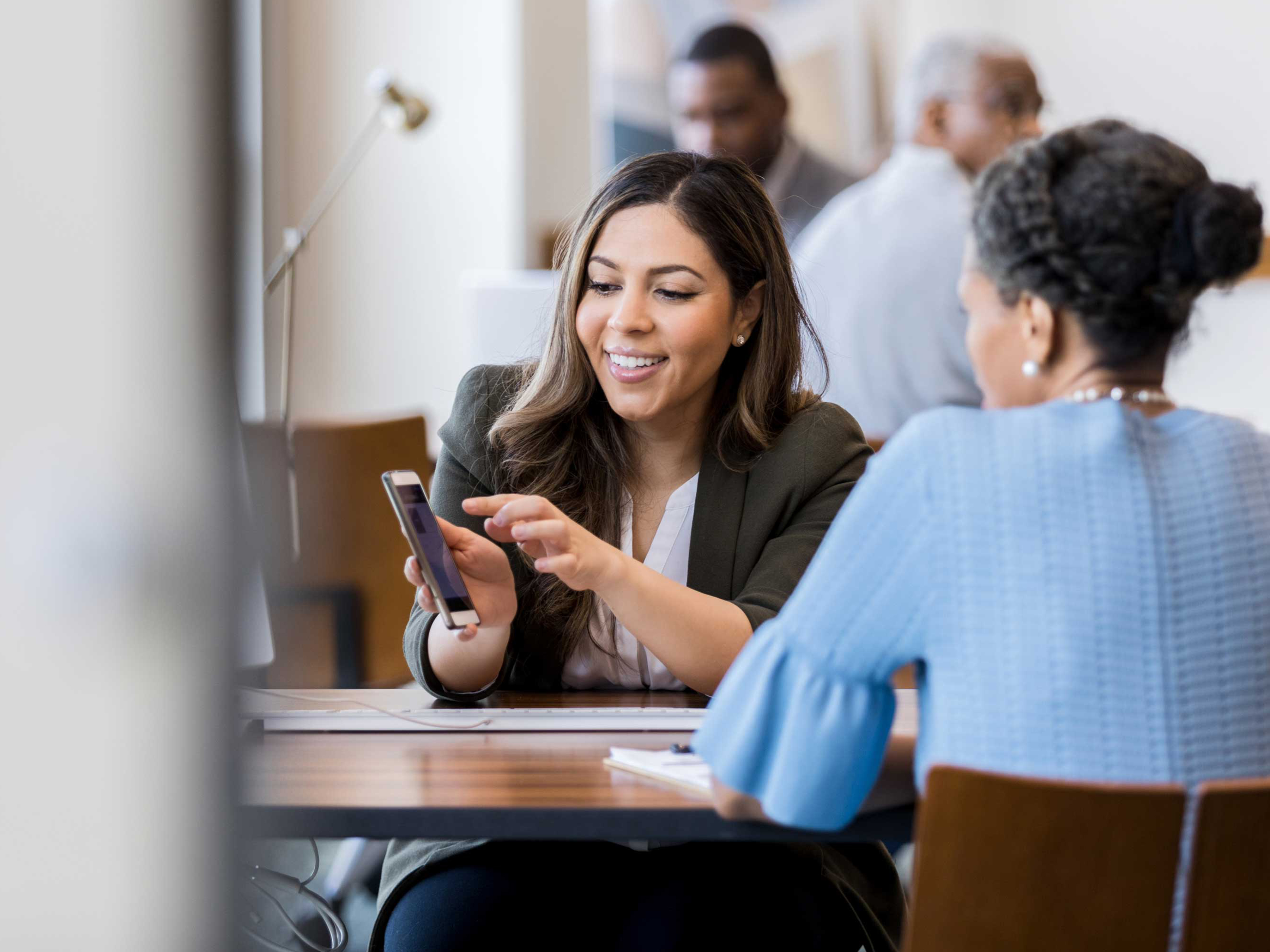 A colleague is showing their mobile computer to a co-worker in professional setting.