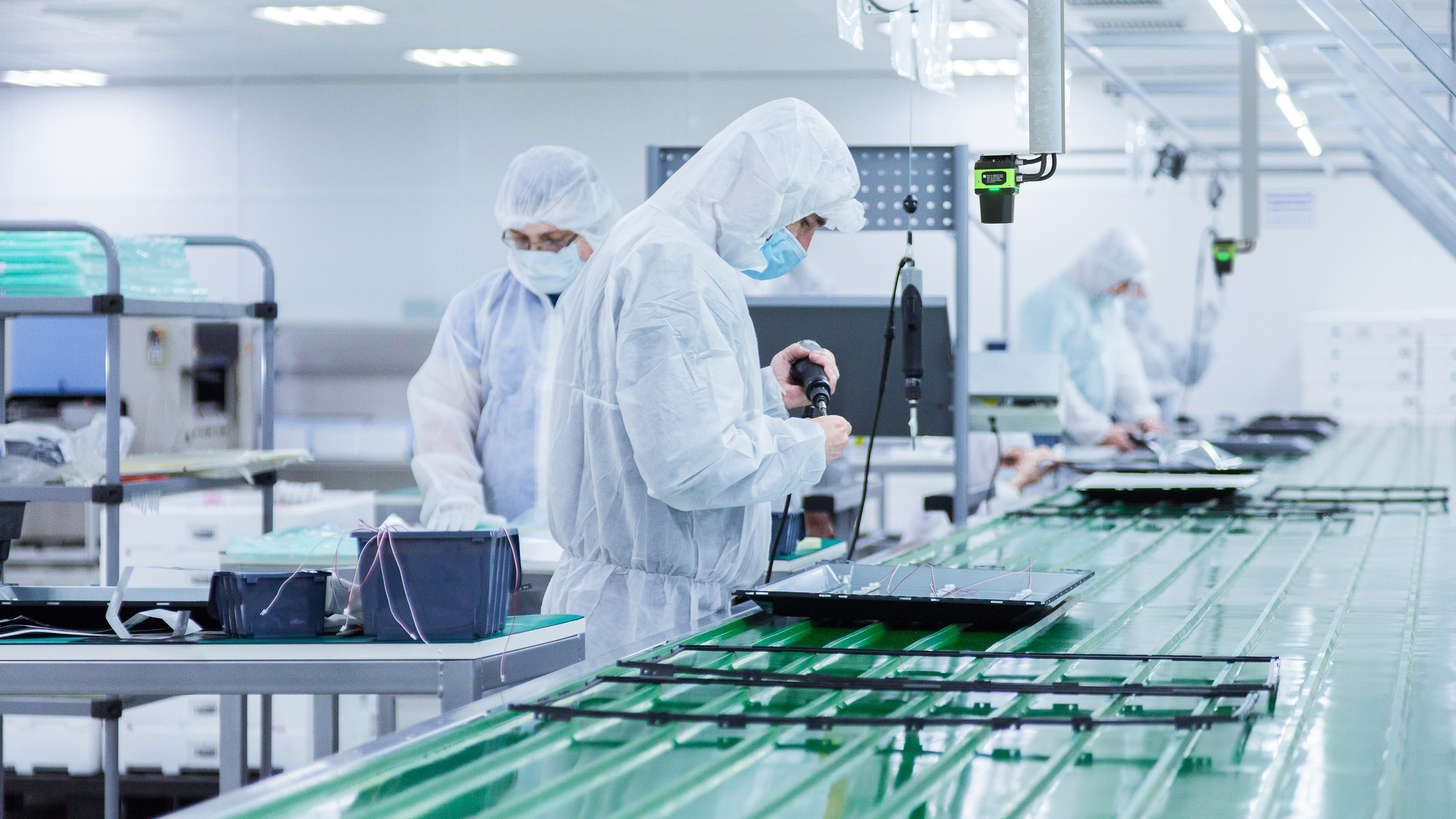 Cleanroom production operators at work wearing cleanroom suits