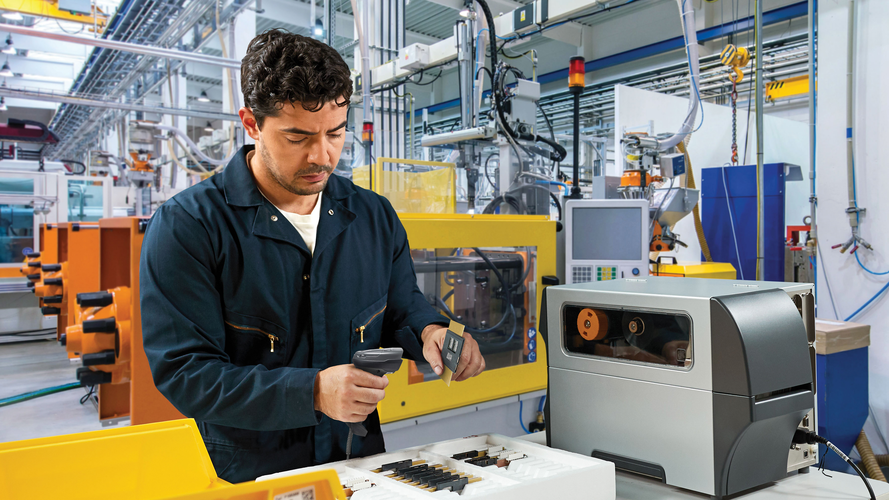 Worker using a Zebra handheld scanner in a manufacturing setting.