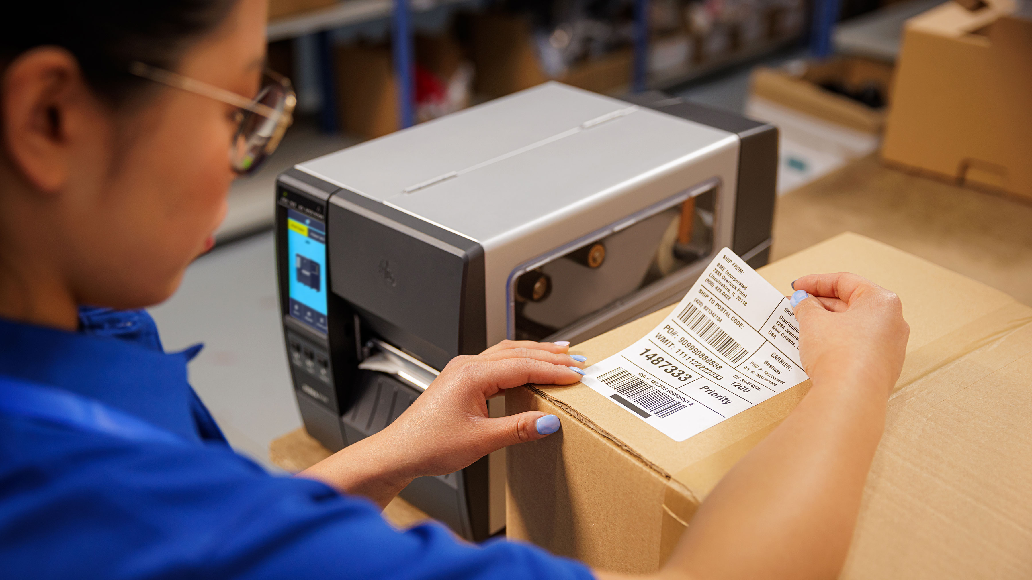 Worker placing a label on a box printed by a Zebra industrial scanner. 