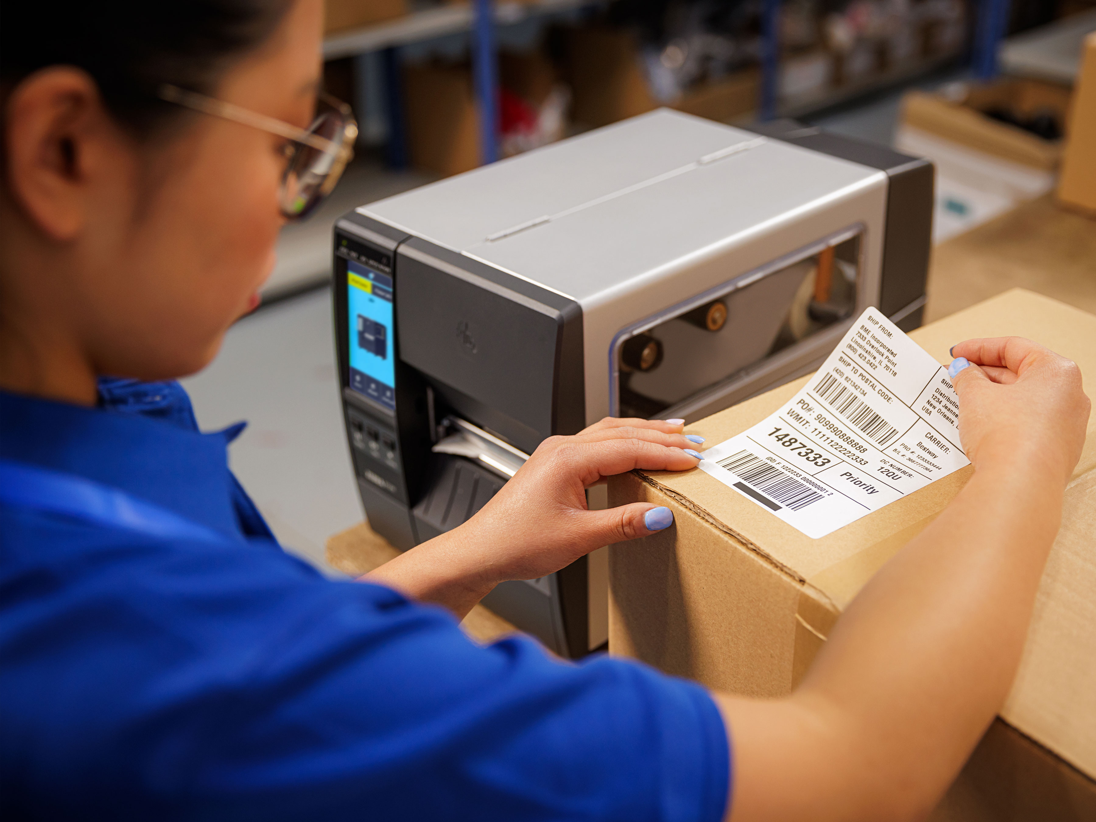 Worker placing a label on a box printed by a Zebra industrial scanner.