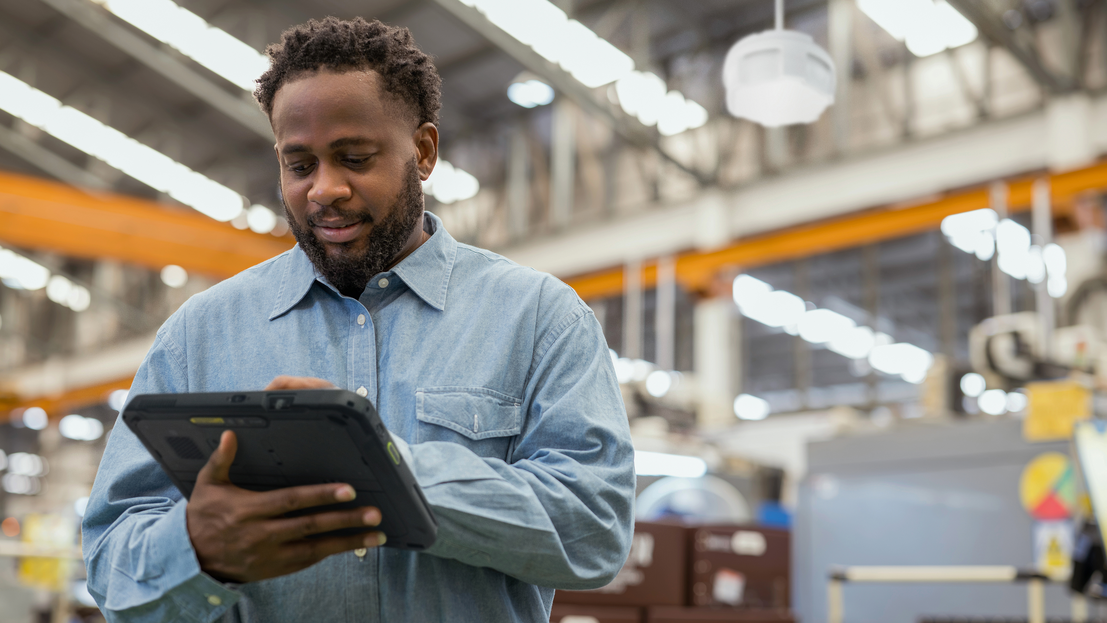 Manufacturing worker using a Zebra rugged tablet on factory floor.