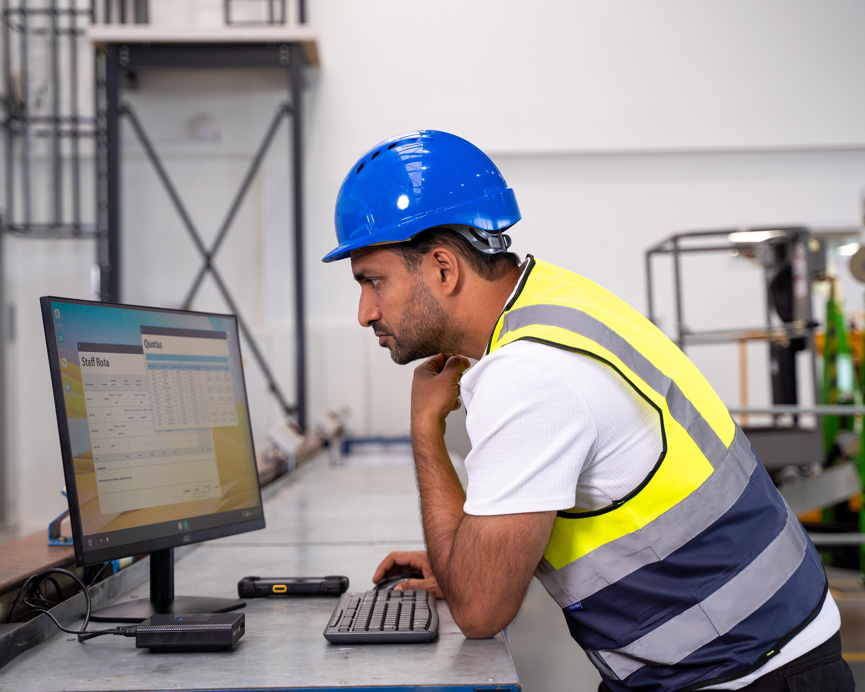 Manufacturing worker using ZEC500 with Workstation Connect and TC73 to review dashboards on digital display.