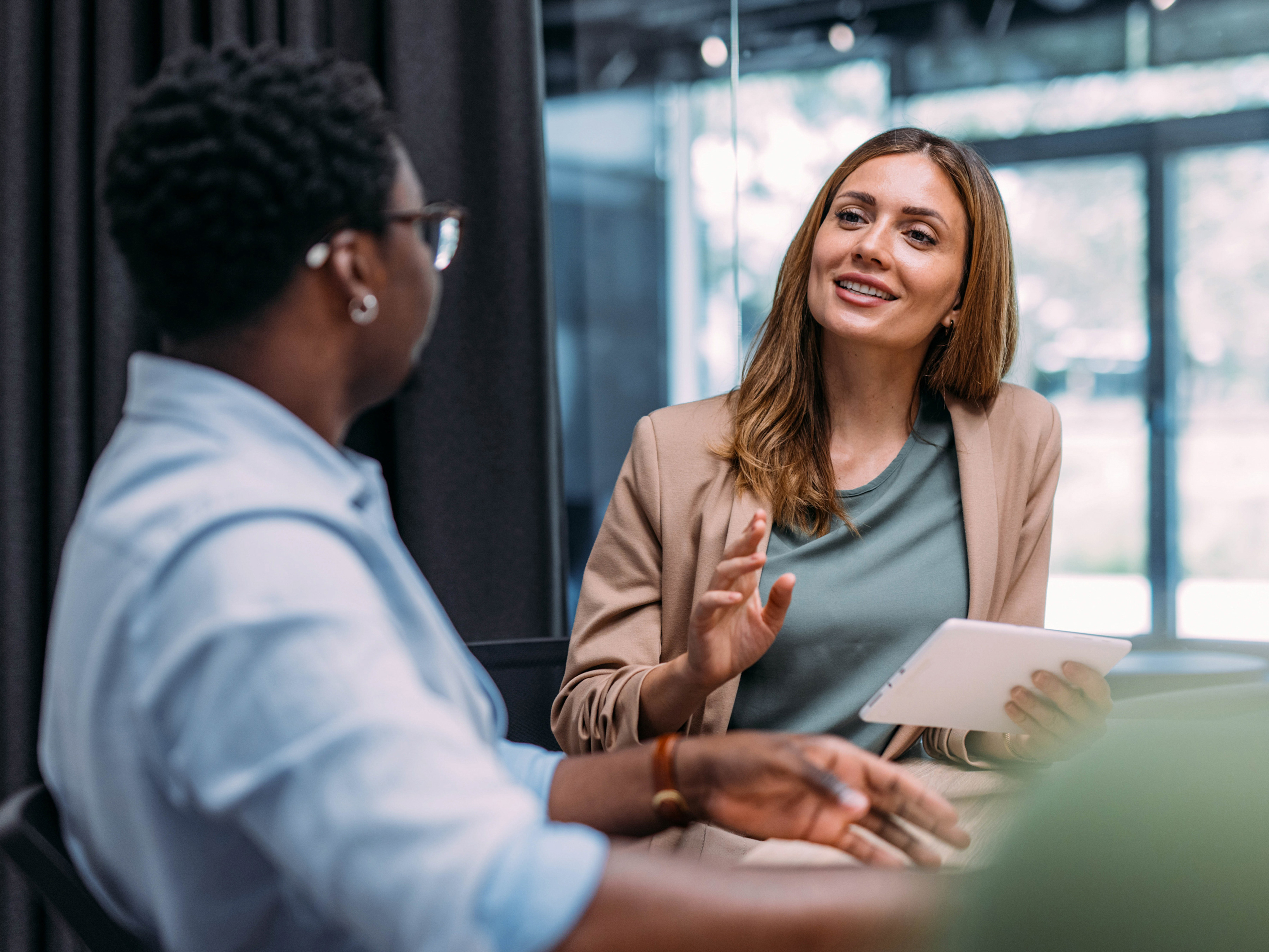 Female employee holding a white table while talking to a male colleague during a meeting