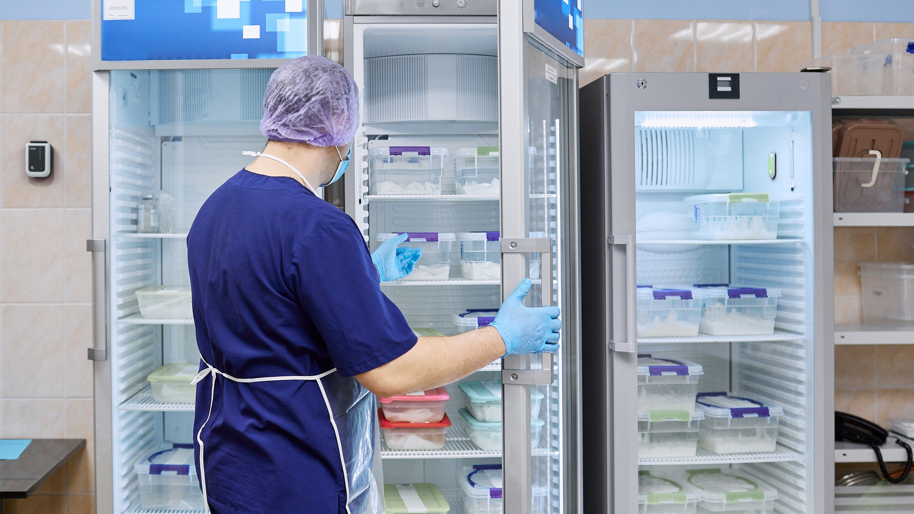 A technician opening a refrigerator to check medical units