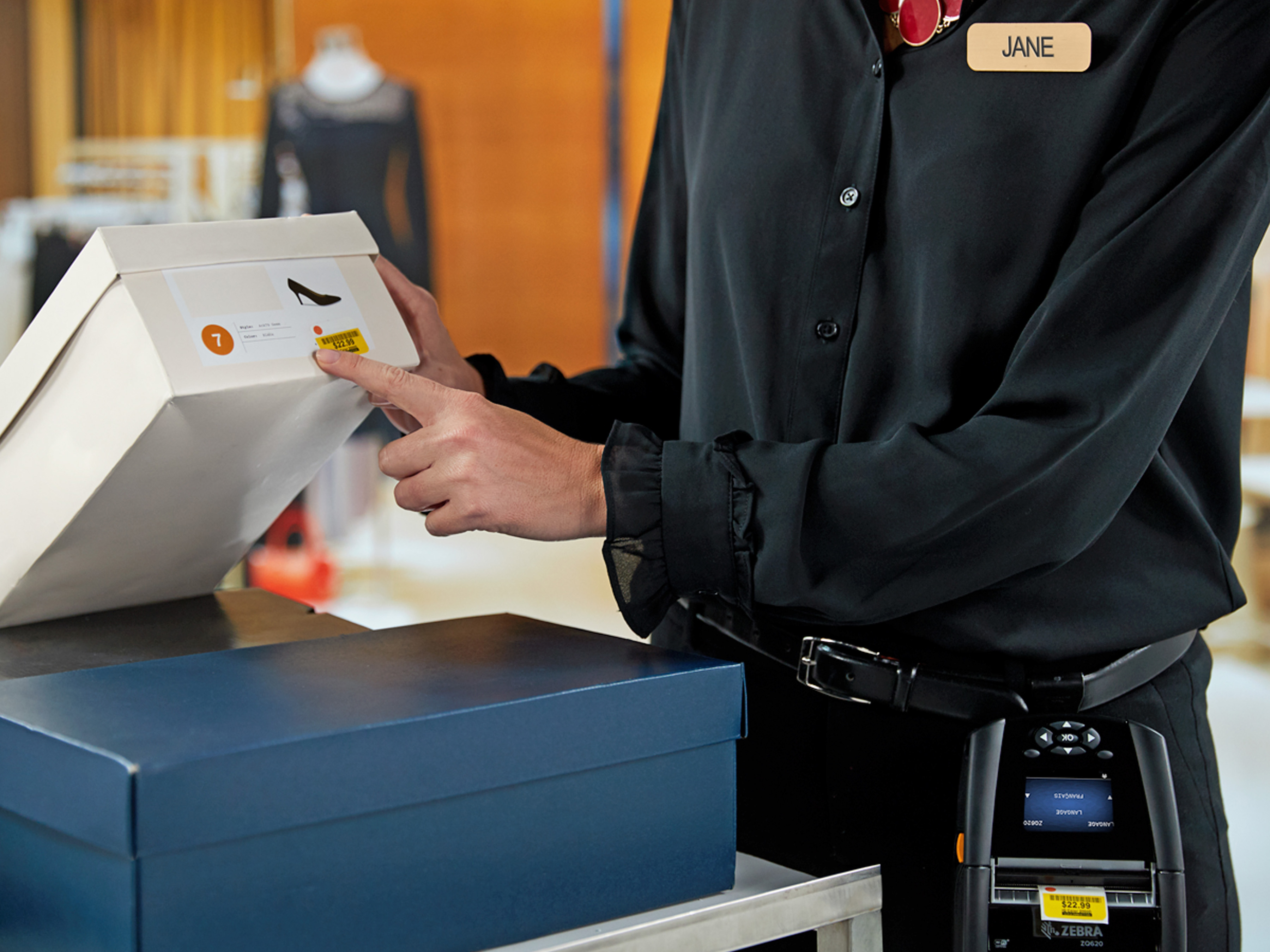 Retail worker applying a label to a shoe box using a Zebra Mobile Printer.