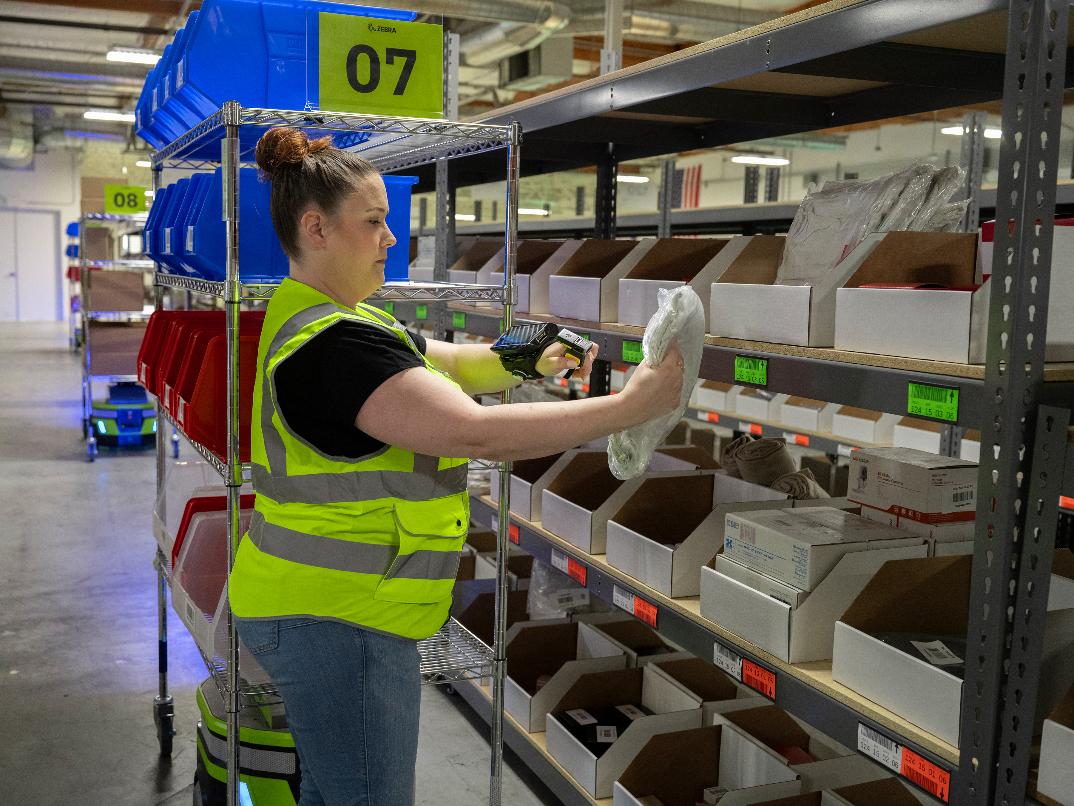 Warehouse worker scanning an item with Zebra mobile robot next to her