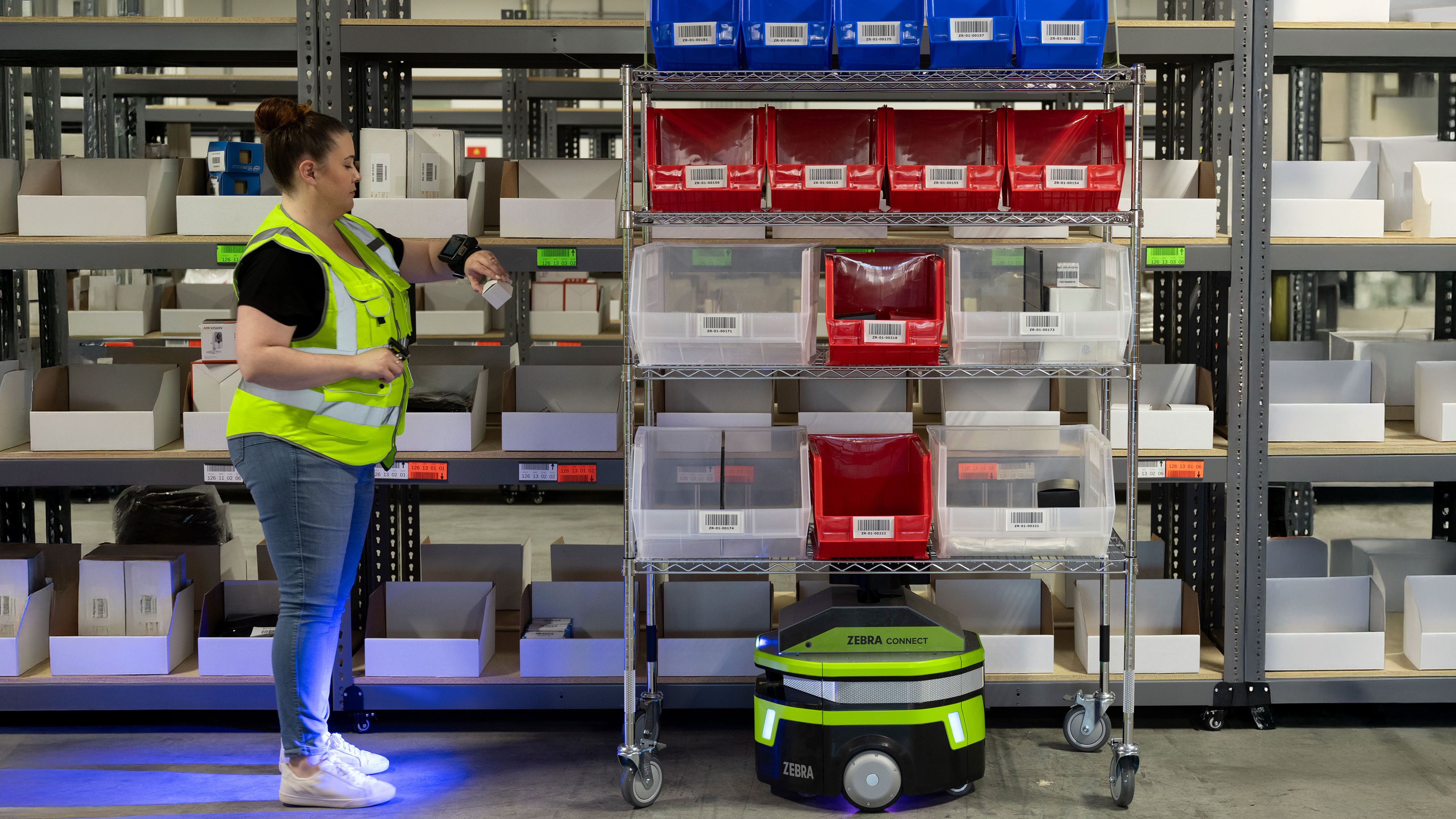 Zebra mobile robot next to an employee scanning item on the shelves