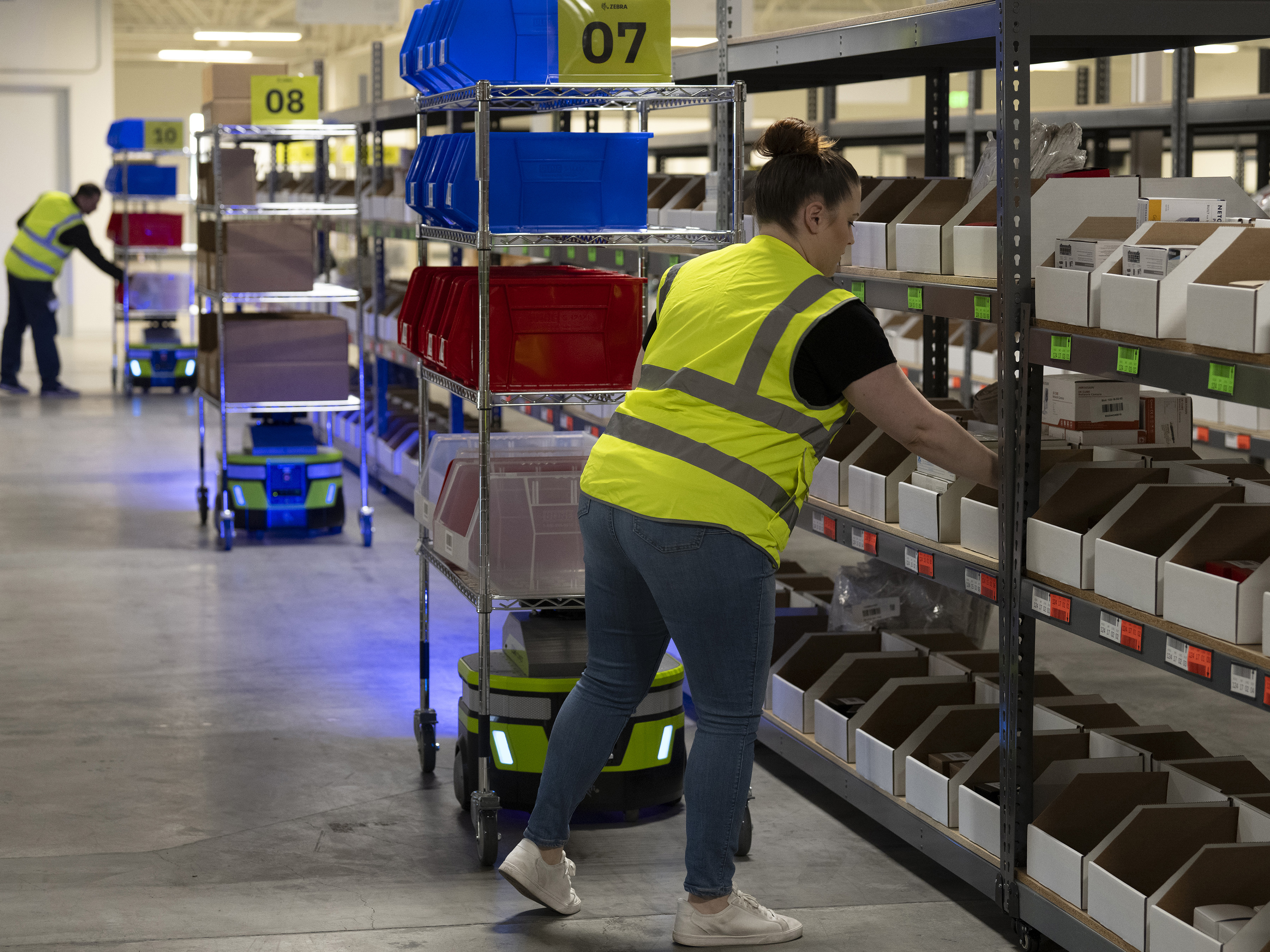 Warehouse workers organizing the shelves with Zebra mobile robots