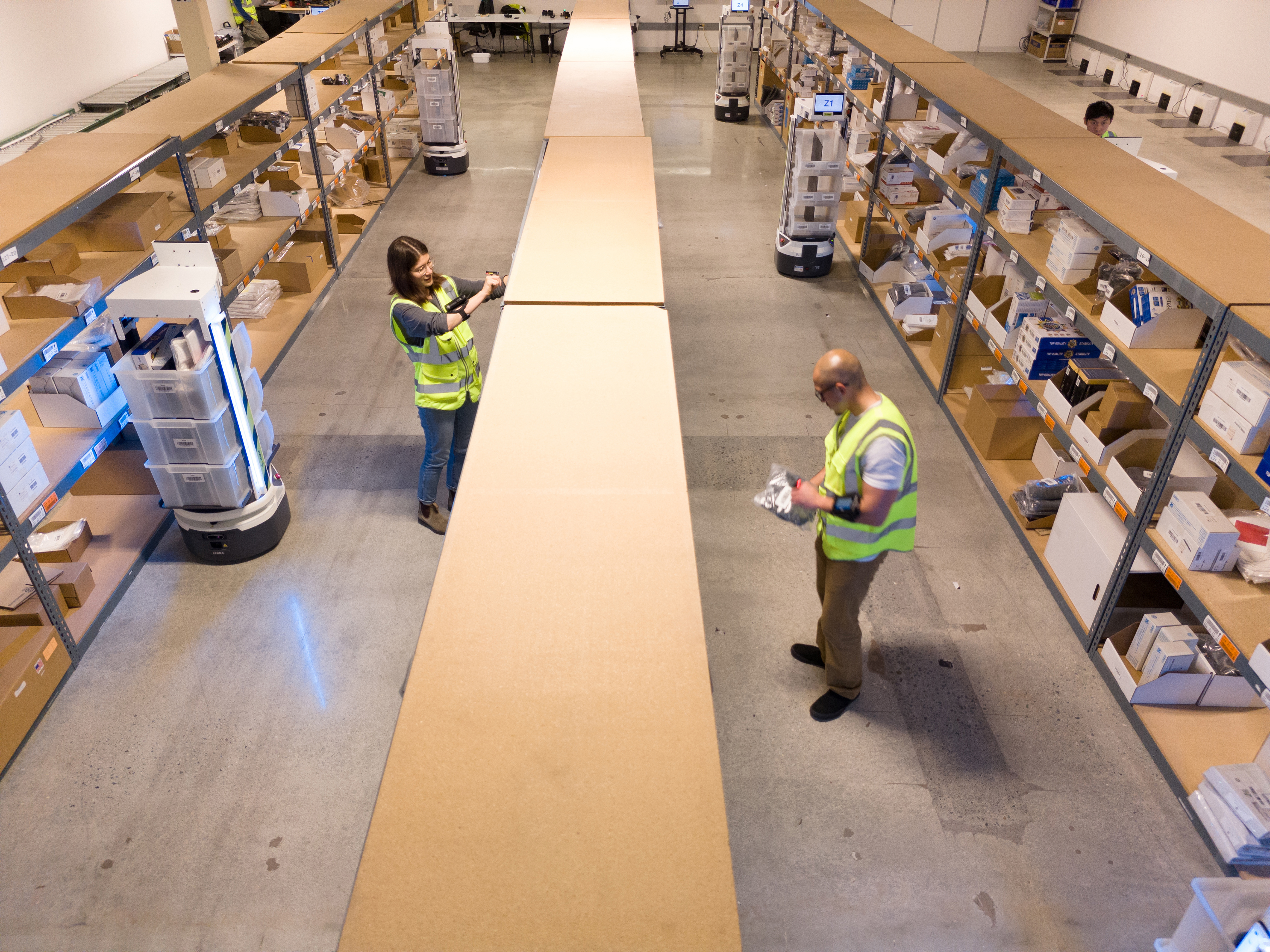 Two workers and Zebra mobile robots inside a warehouse