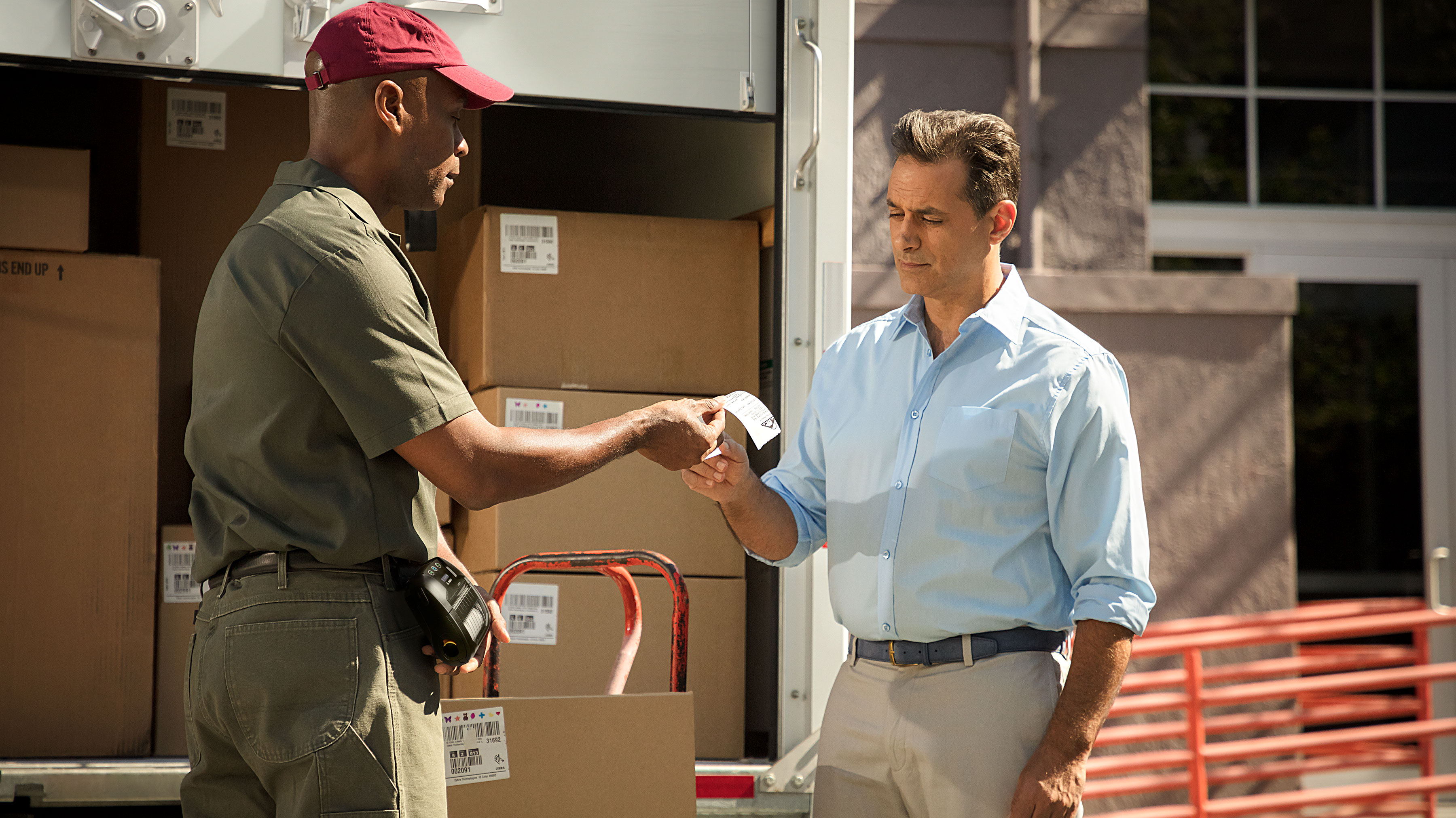 Delivery personnel giving a customer a receipt that was printed on a Zebra mobile printer.