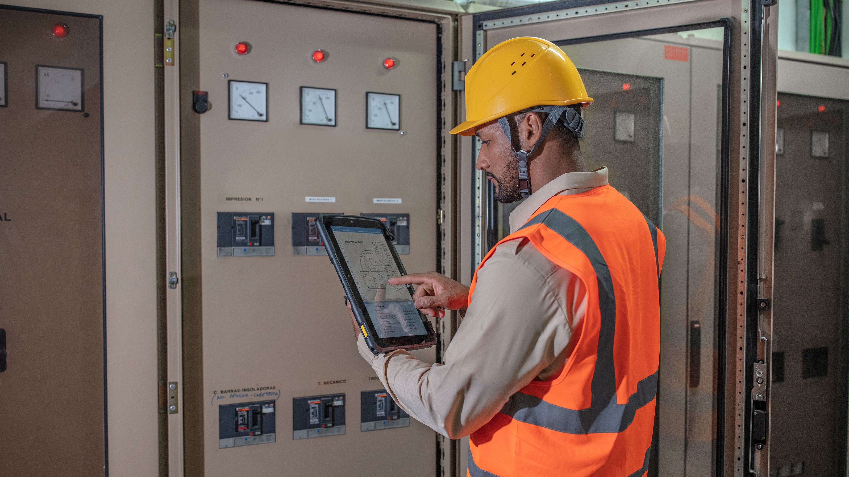 Technician working a control panel with a Zebra tablet.