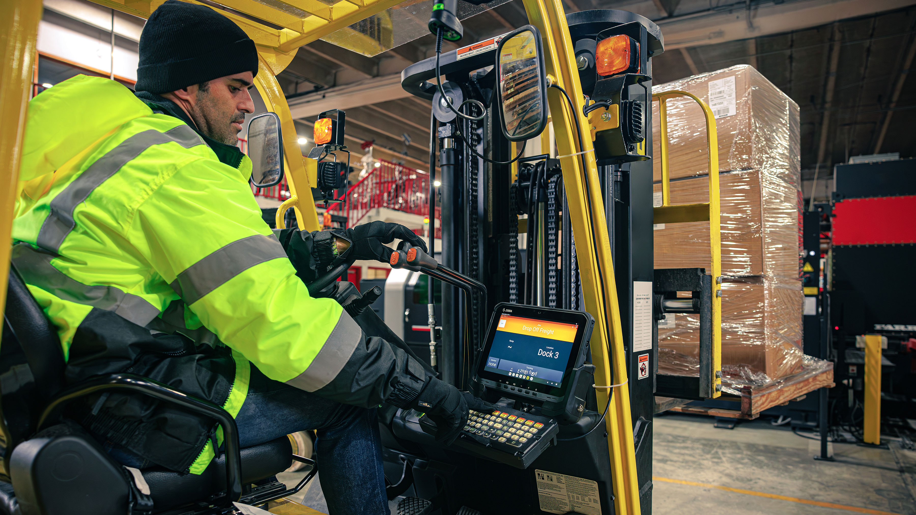 Warehouse worker operating a forklift and using a Zebra mounted tablet.