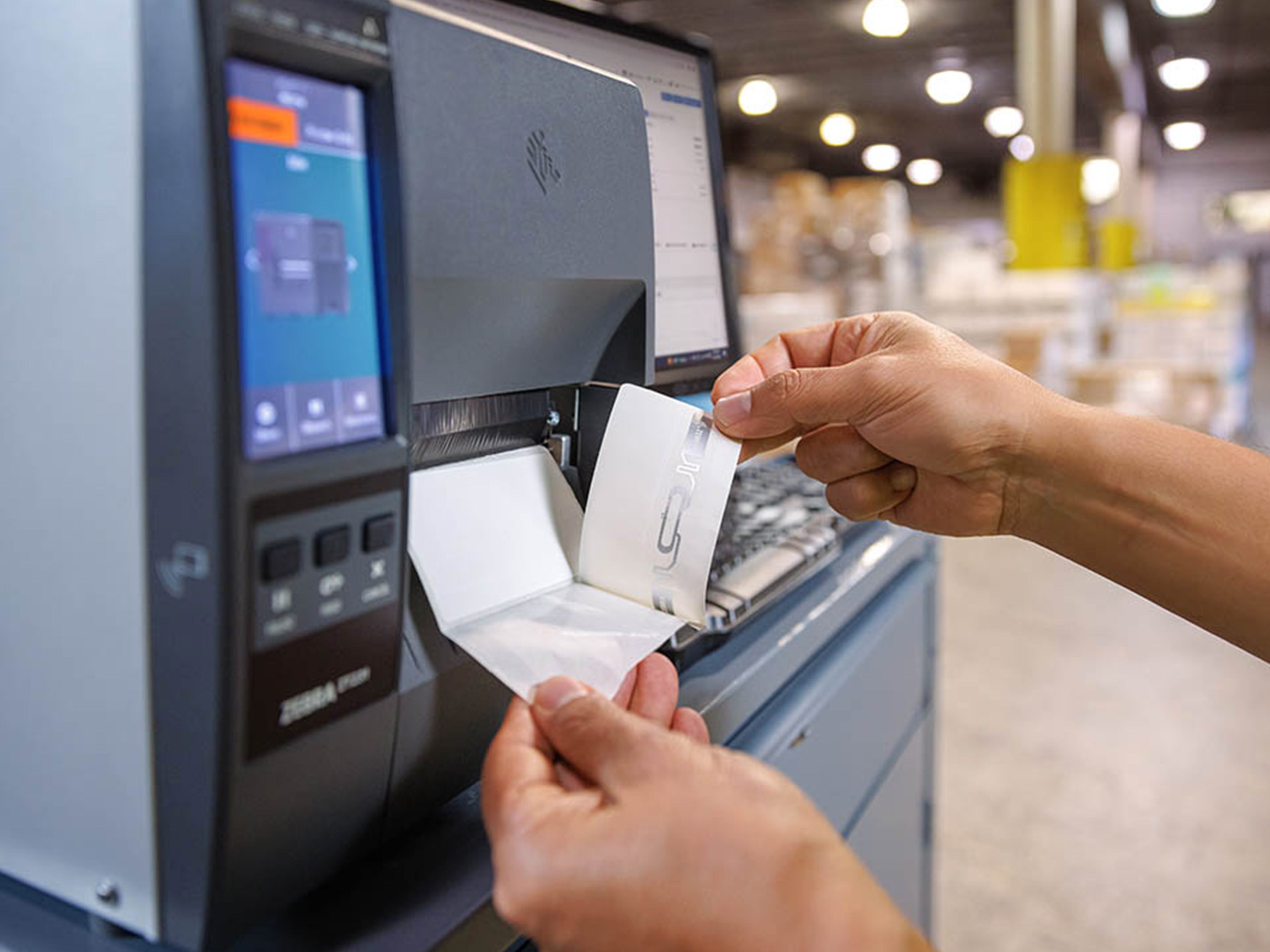 Warehouse worker printing a label using a Zebra industrial printer.