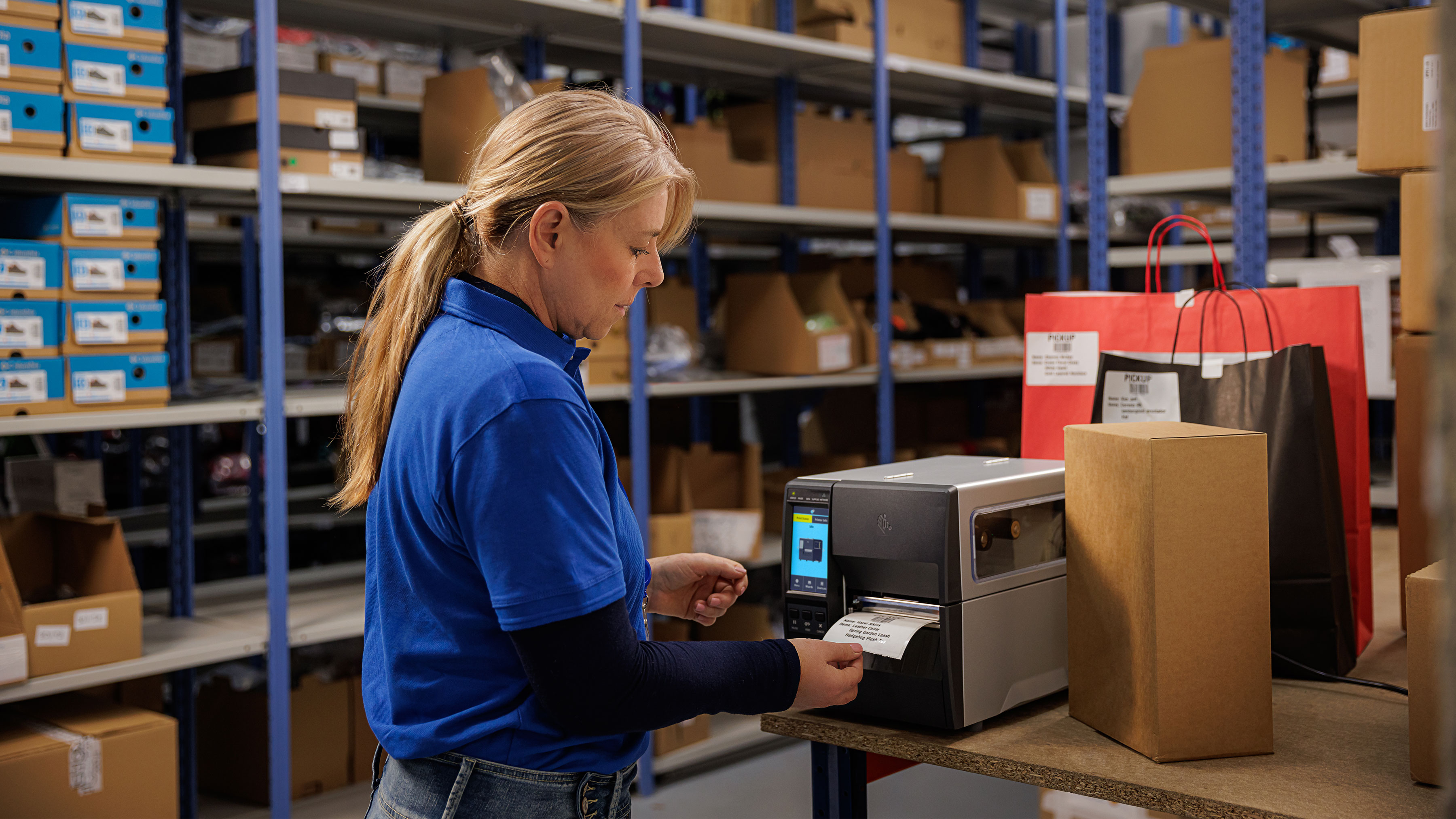 Warehouse working printing a label using a Zebra industrial printer in a stockroom.