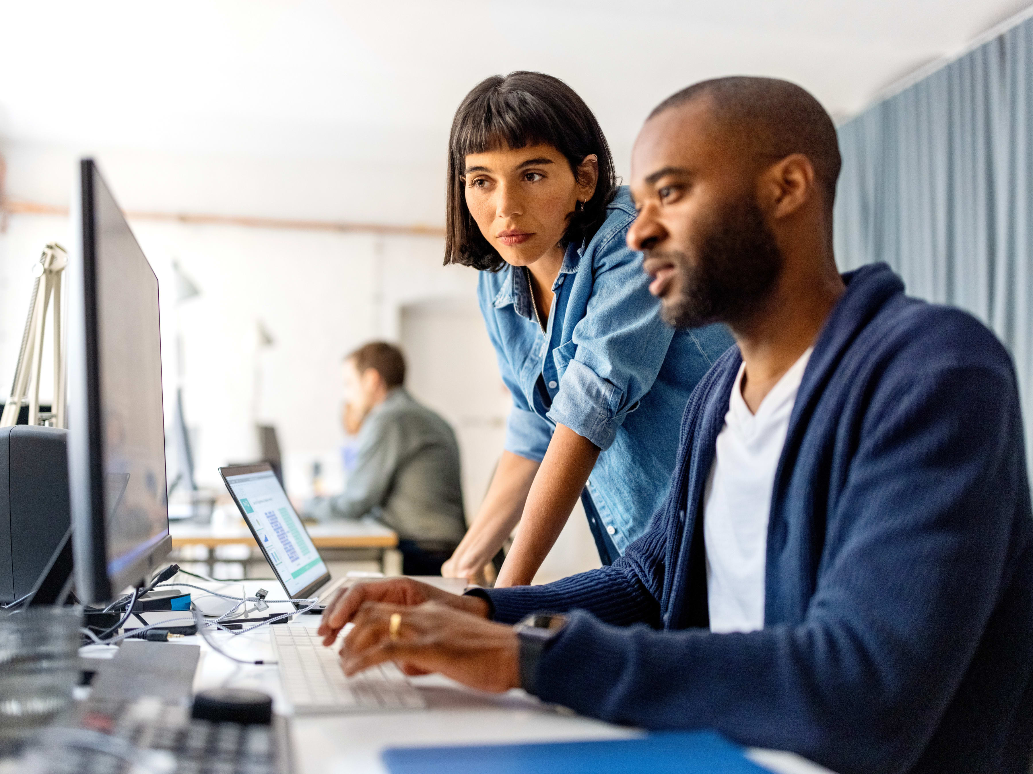 Two workers collaborating at a workstation inside a modern office space.