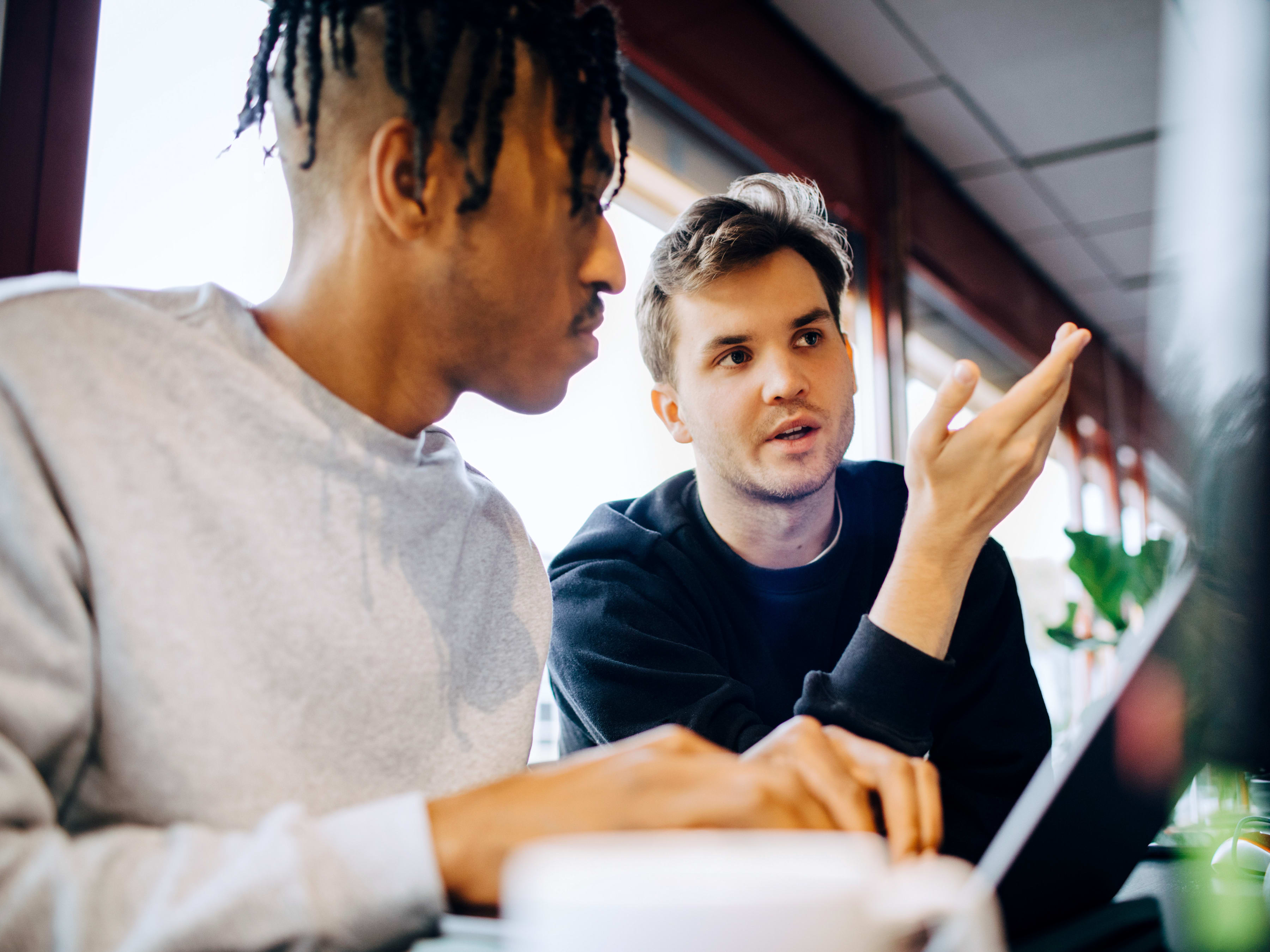 Two coworkers collaborating inside a casual office setting.