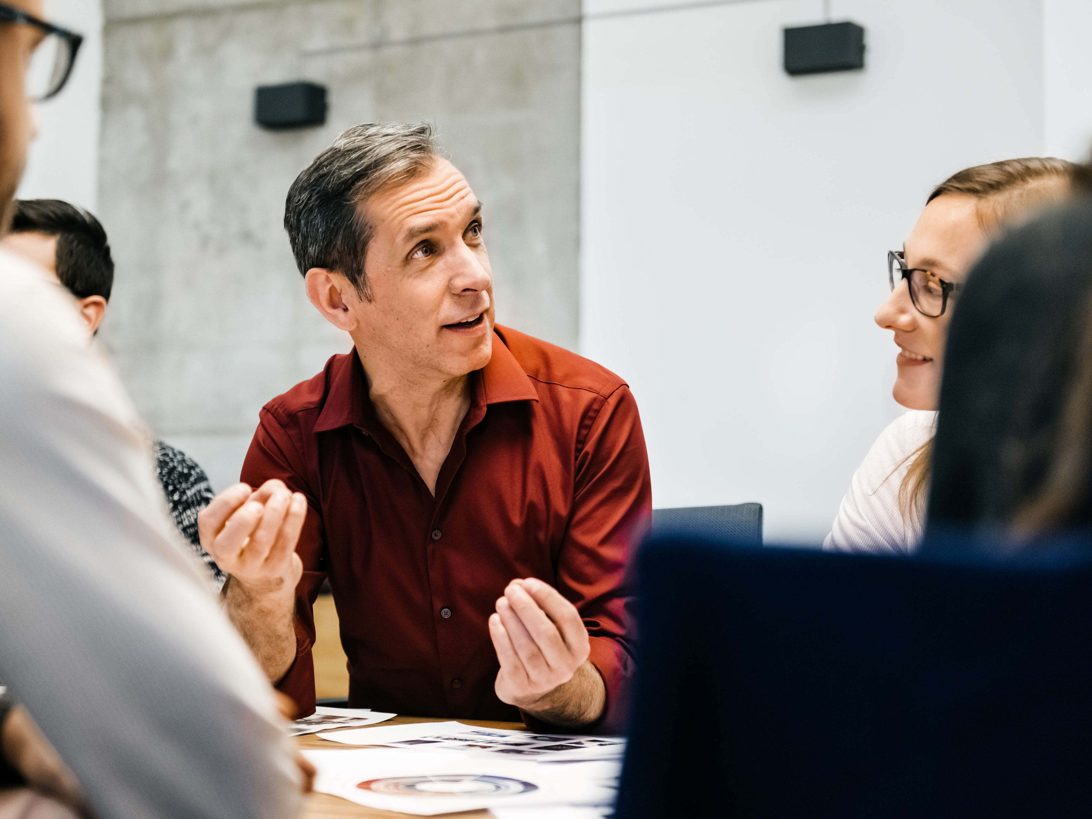 A group of colleagues are engaged in a discussion around a table in a conference room.