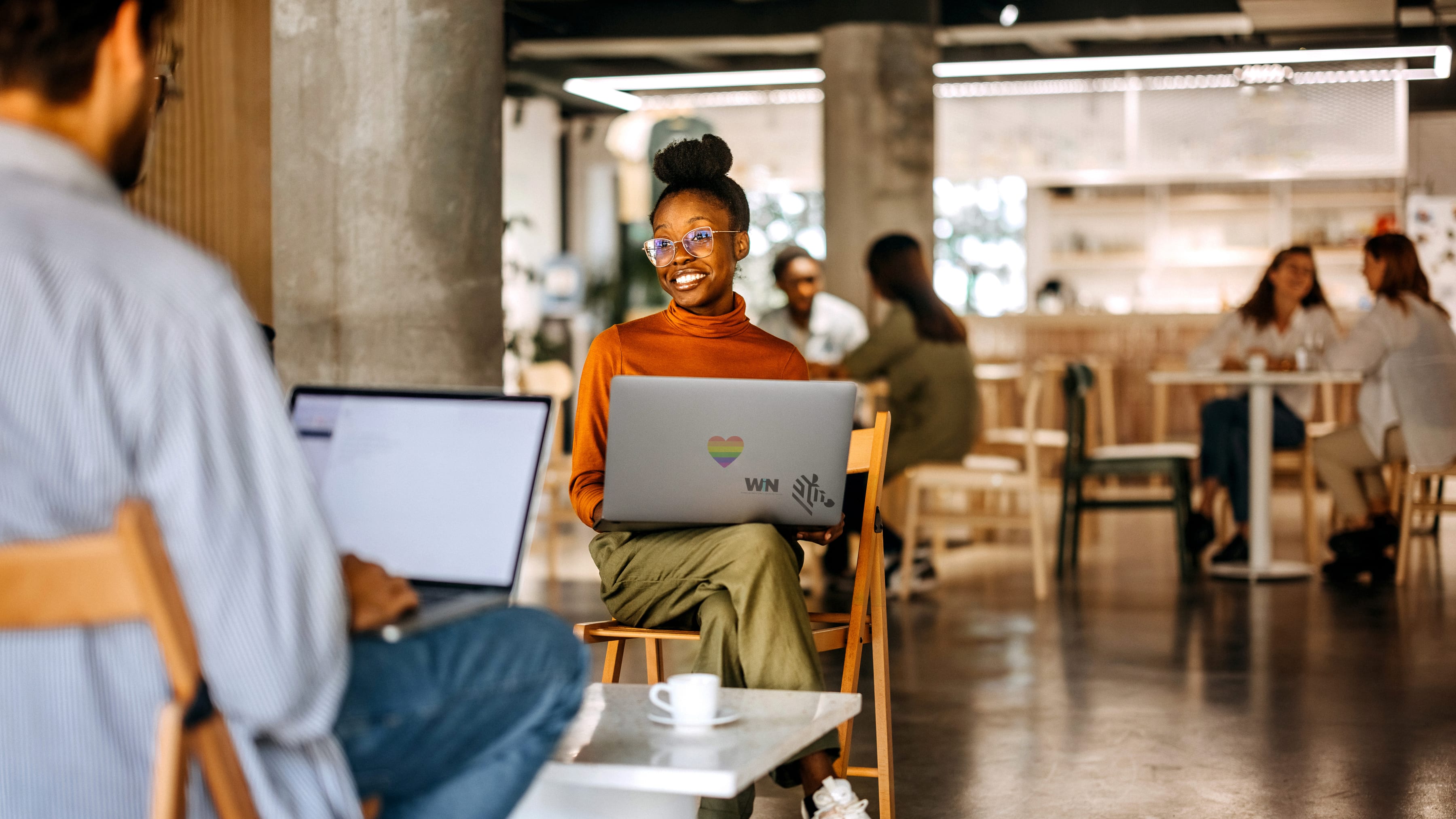 Two employees with laptops talking inside of a co-working space.