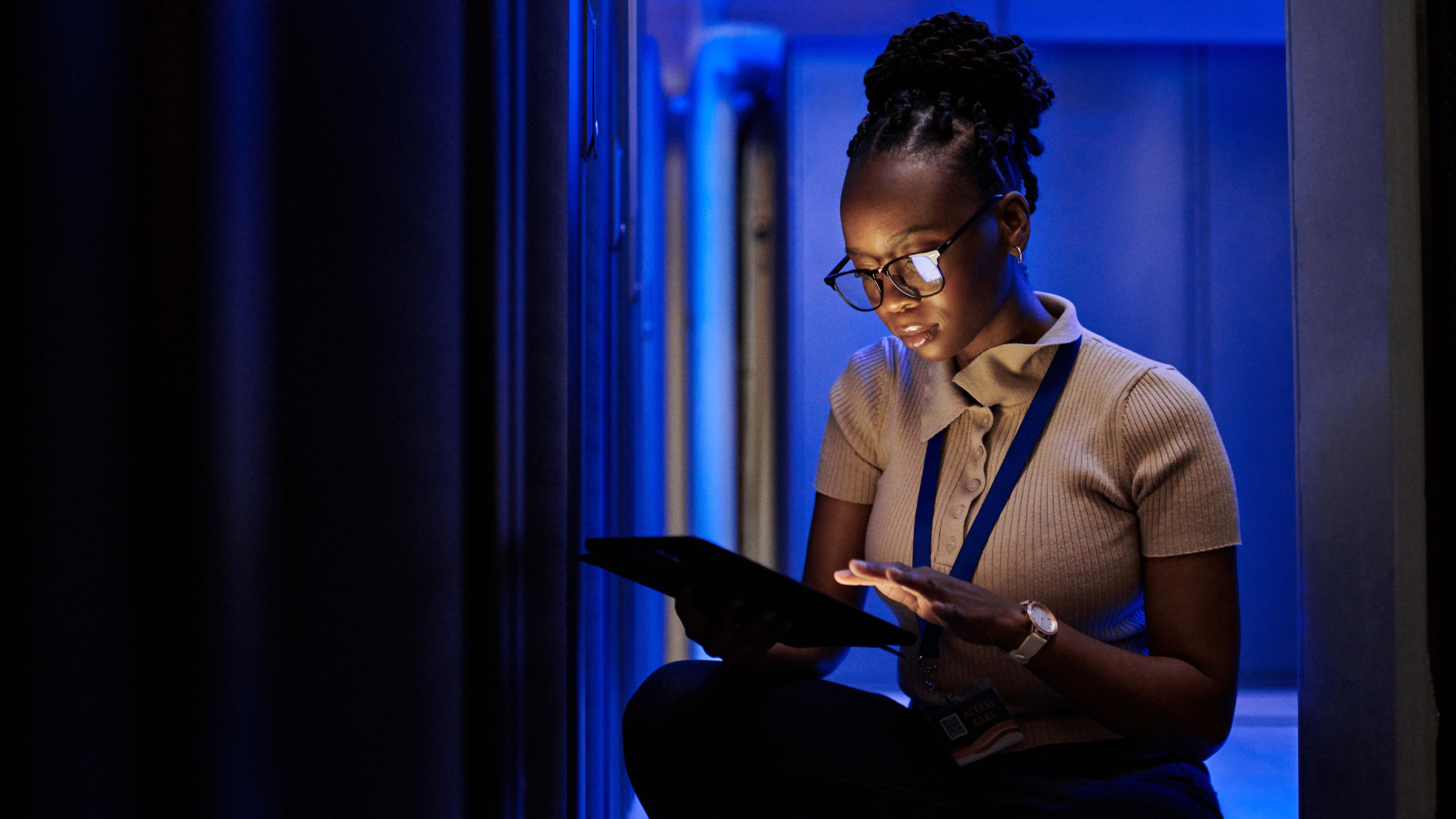 An IT professional is using a tablet to monitor and manage the server racks.